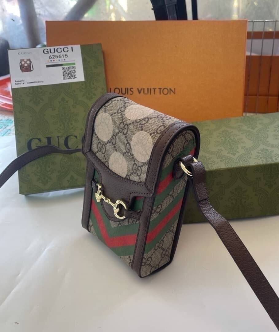 VIP 】GG CANVAS AND LEATHER CROSS-BODY PHONE BAG พร้อมส่งที่ไทย Brown canvas Brown Ophidia GG Supreme mini bag from GUCCI featuring an adjustable shoulder strap, a foldover top, a GG Supreme pattern, a Web stripe to the front and a gold-tone Double G plaqu