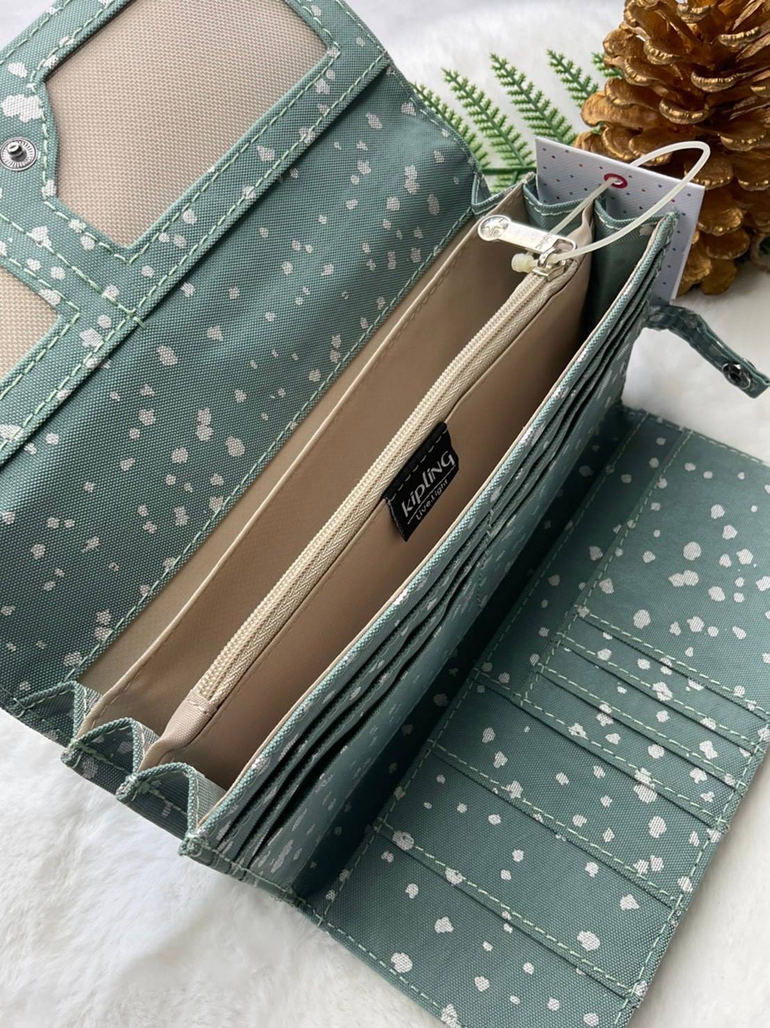 กระเป๋าสตางค์ยาว 3 พับตอน Kipling Brownie long tri-fold wallets กระเป๋าสตางค์ยาวแบบ3พับตอน วัสดุกันน้ำ เปิดปิดด้วยกระดุมแป๊ก มีช่องใส่ธนบัตรหลายช่อง ช่องเสียบการด์ได้ถึง13ช่องลายจุด และใส่รูปภาพได้อีก2ช่อง ช่องซิปใส่เหรียญ ช่องธนบัตร 3 ช่อง ที่จับหัวซิปปั