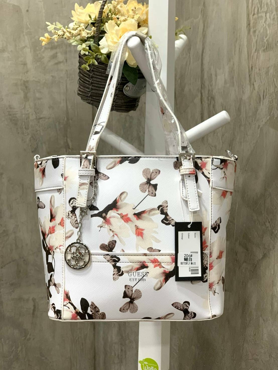 GUESS Women's Medium Floral Tote Bag กระเป๋าถือ คล้องไหล่หรือสะพาย ขนาดกลาง วัสดุหนังpu ลายดอกไม้ชนิดต่างๆรอบใบ เปิดปิดใช้งานด้วยซิปเดียวด้านบน ภายในมีกว้างใส่กระเป๋าสตาวค์ยาว มินิไอแพคได้ หูจับและสายสะพายปรับระดับได้ มาพร้อมกุญแจโลโก้guess สวยน่ารัก