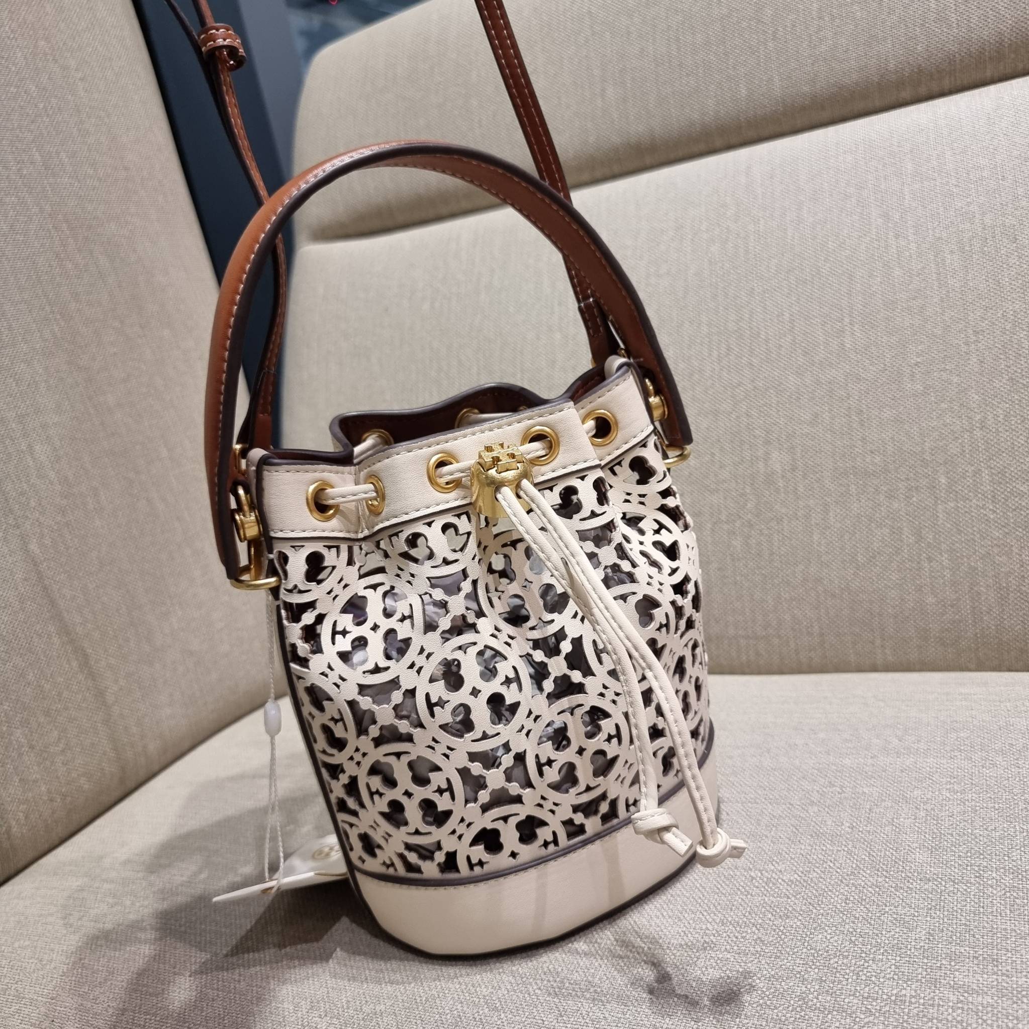 TORY BURCH T MONOGRAM LASER-CUT MINI BUCKET BAG ใจบางที่สุดกับคอลเลคชั่นนี้ กับกระเป๋าสะพายทรงบัคเก็ต ไซส์มินิ รุ่นชูโรงสุดฮิต ที่เพิ่มดีเทลความแพงด้วยการฉลุลวดลายโมโนแกรมรอบใบ ถักทอเป็นเส้นลายสานที่สวยงามมาก งานฝีมือจริงๆ วัสดุหนัง cowhide รูดเปิด-ปิดด้ว