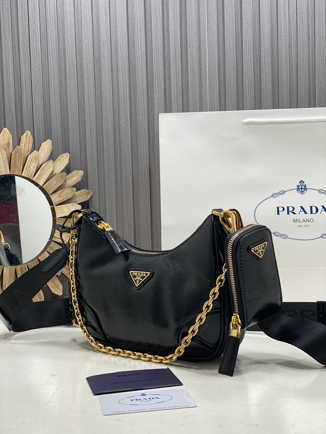 ORI หนังแท้ | Prada Re-Edition 2005 bag in Naplak leather กระเป๋าสะพายทรงโฮโบหนังแก้ว ดีไซน์เอฟเฟกต์มันวาวและเท็กซ์เจอร์ที่มีเสน่ห์สไตล์วินเทจ พร้อมทริกห้อยเพิ่มสไตล์สัมผัสที่โดดเด่นและร่วมสมัยยิ่งขึ้น