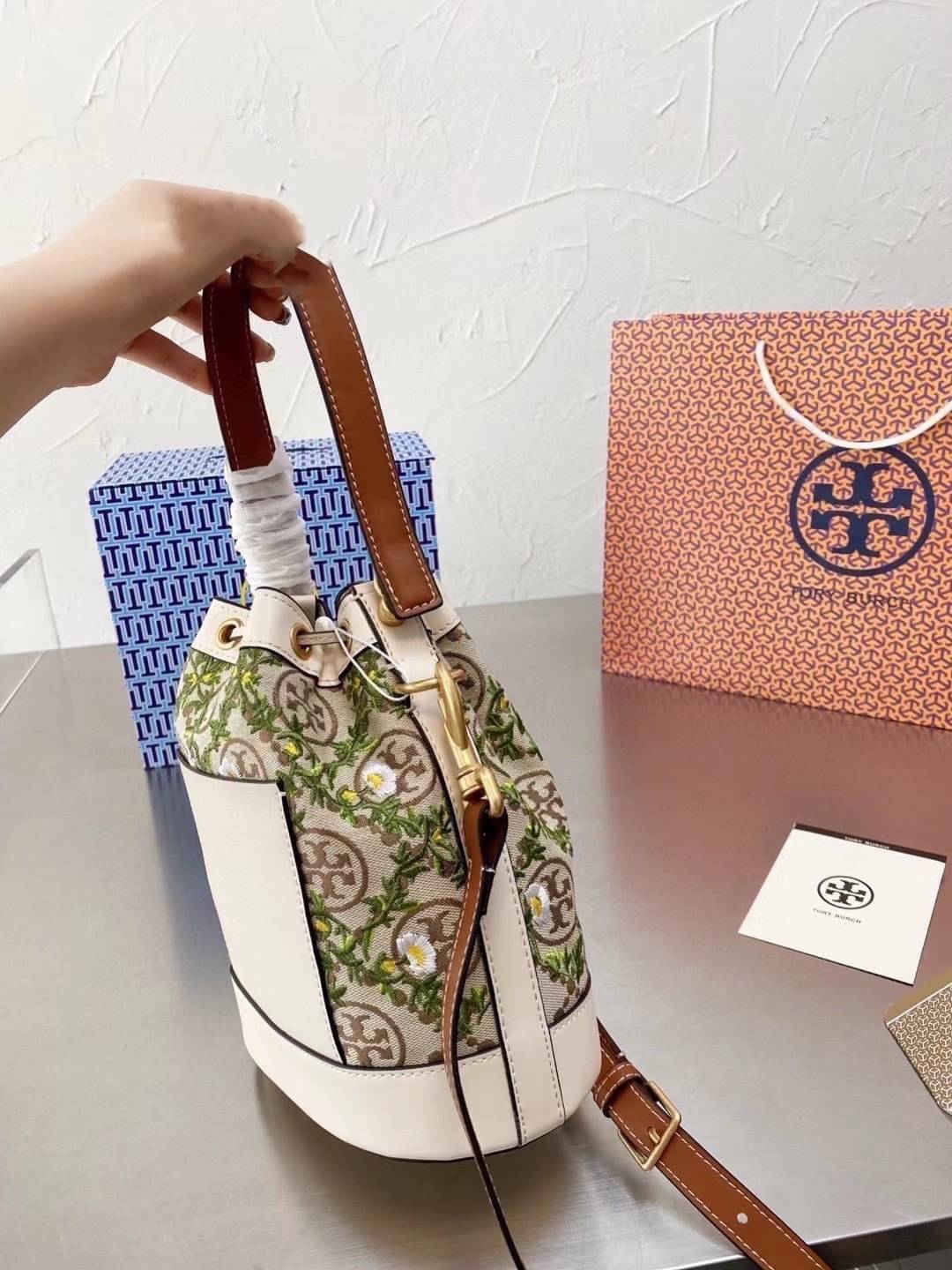 TORY BURCH T MONOGRAM JACQUARD EMBROIDERED BUCKET BAG ครั้งแรกกับโมโนแกรม ที่ได้รับแรงบันดาลใจมาจากโลโก้สุดคลาสสิก กลับมาอีกครั้งในรูปแบบของ ลวดลาย T Monogram ที่ผสมผสานความร่วมสมัยเข้ากับความเป็นเอกลักษณ์ของแบรนด์เข้าไว้ด้วยกัน โดยเป็นการนำเอาลวดลาย T Mo