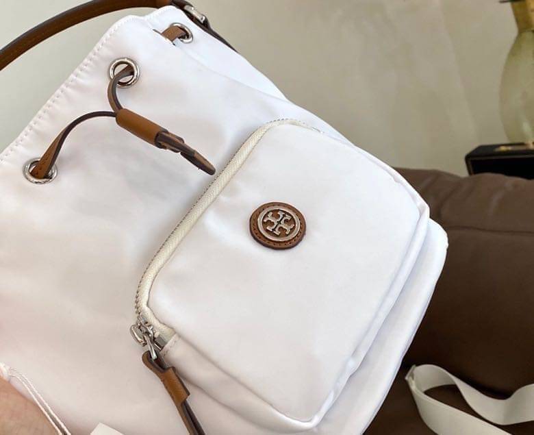 Tory Burch Virginia Nylon Bucket Bag / Tory Burch logo-plaque bucket bag กระเป๋าสะพายทรงบัคเก็ต เปิด-ปิดหนังรูดปากกระเป๋า มีหูหิ้วในตัว คล้องแขนเก๋ๆ ภายในเป็นช่องโล่ง มีช่องย่อย ใส่ของสำคัญจุกจิกได้ มีสายครอส จะสะพายไปไหนก็ได้ทุกโอกาส สวยเลิศทุกสี พร้อมส่