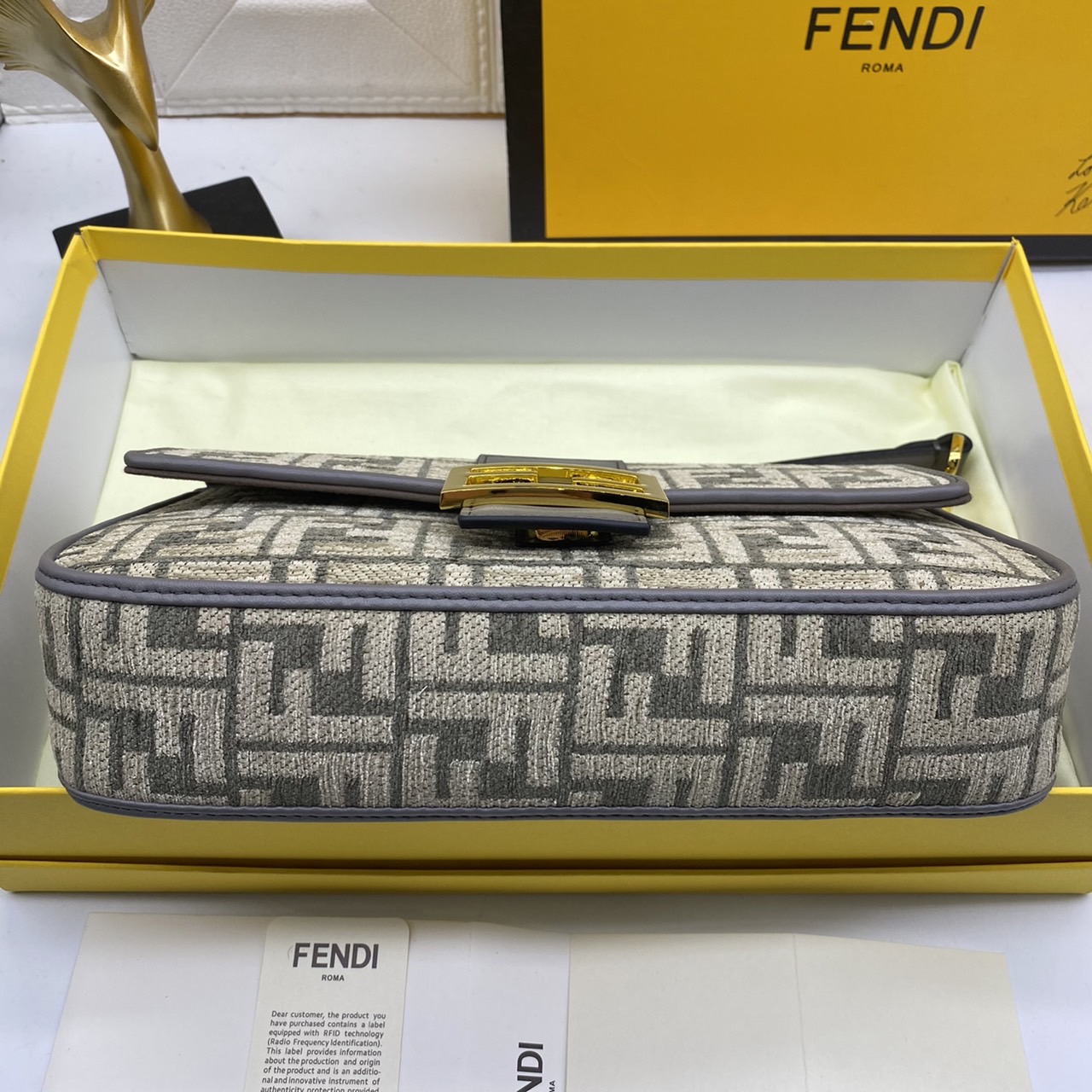 Fendi Baguette FF Tapestry Fabric Bag เกรดออริจินอล กระเป๋าทรง Baguette ขนาดกลาง วัสดุผ้าเซนิล พร้อมลวดลาย FF สีเทาเข้ม ปิดท้ายด้วยรายละเอียดหนังแบบทูโทนและประดับด้วยตัวล็อค FF โดดเด่นด้วยฝาปิดด้านหน้าตัวล็อคแม่เหล็กช่องด้านในบุด้วยผ้าหนังกลับพร้อมกระเป๋า