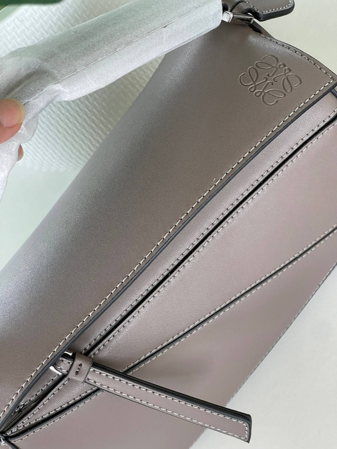 Loewe Puzzle Bag In Classic กระเป๋าทรง Puzzle นี้ออกแบบโดย Jonathan Anderson โดยได้รับแรงบันดาลใจในการออกแบบมาจากรูปทรงของลูกรักบี้ ดังนั้น จึงจะเห็นได้ว่าการตัดเย็บและรูปทรงของกระเป๋านั้นคล้ายคลึงกับลูกรักบี้ รูปทรงดูมินิมอลไม่ทิ้งคอนเซ็ปต์ของแบรนด์ สามา