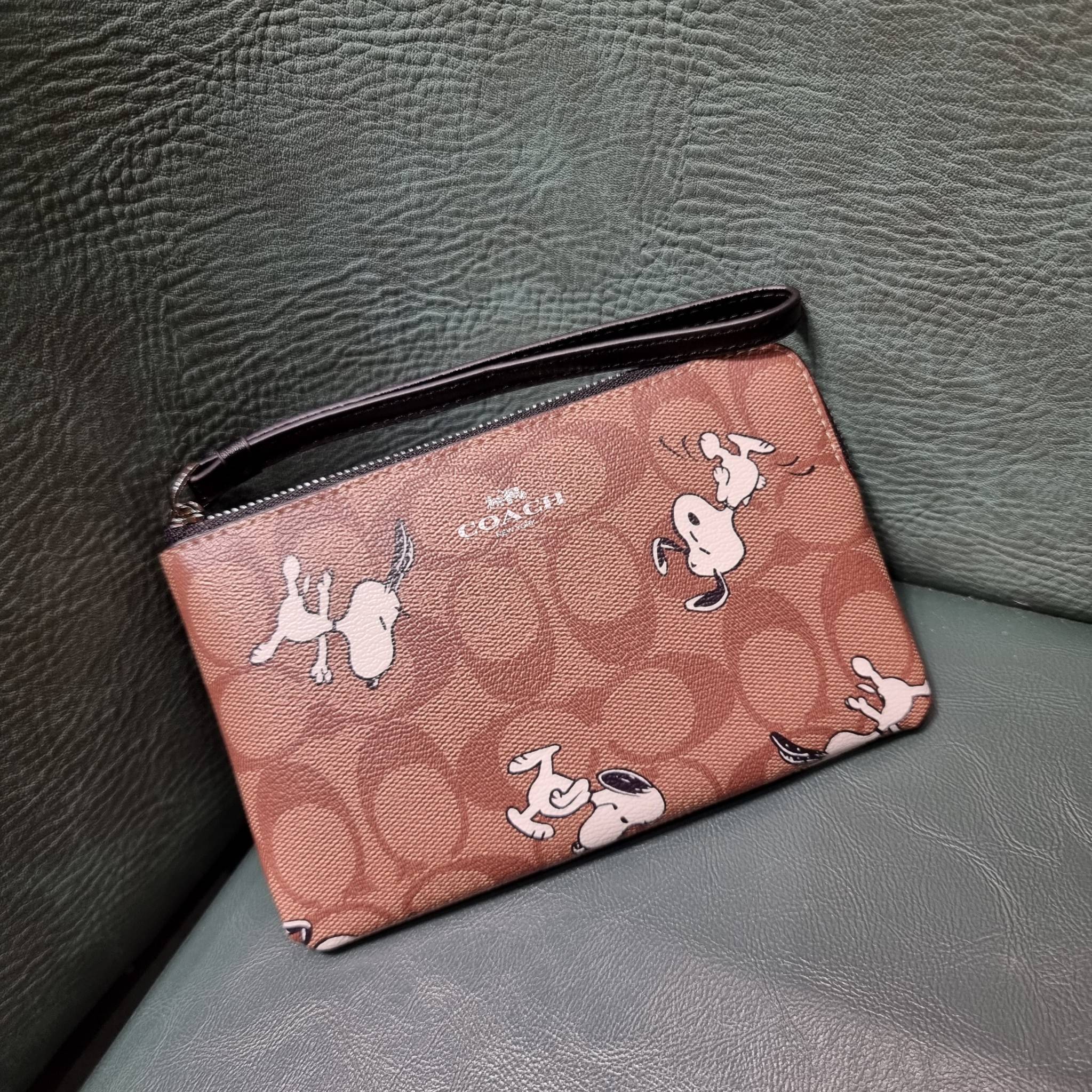 COACH C4589 COACH x PEANUTS CORNER ZIP WRISTLET IN SIGNATURE CANVAS WITH SNOOPY PRINT เหล่าผองเพื่อนและสนูปพีมาแล้วจ้า คอลเลคชั่นสุดน่ารักที่ฮอตไม่มีตก กระเป๋าคล้องมือ ขนาดเหมาะพกพากำลังเหมาะ วัสดุหนังแคนวาสเคลือบลาย ภายในเป็นช่องโล่ง ใส่ธนบัตร หรือใส่บัต
