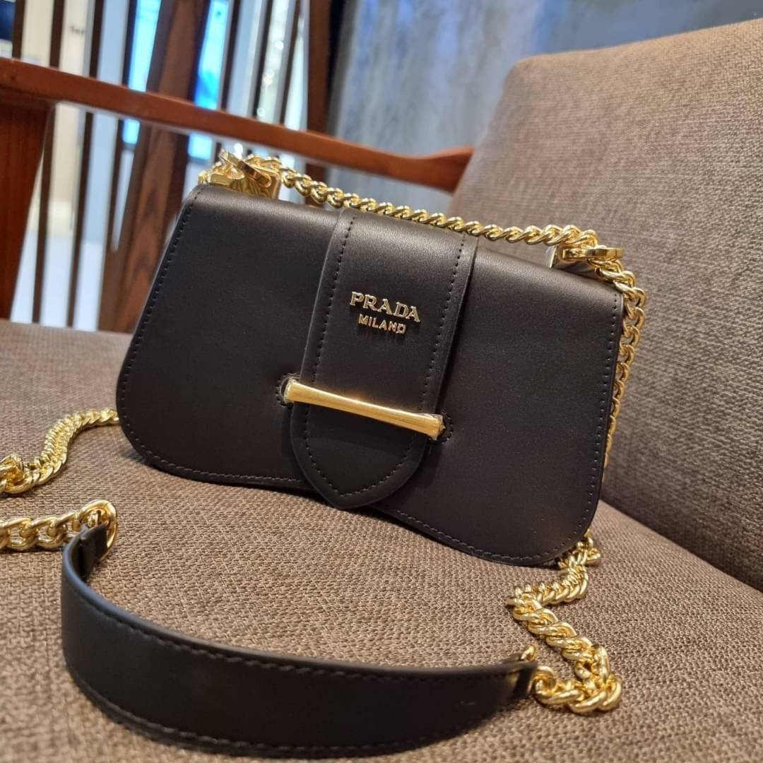 PRADA FRAGRANCE SHOULDER BAG WITH GWP ไอเท็มสุดโปรดที่ควรค่าแก่การครอบครองและเก็บสะสม กระเป๋าสะพายไหล่ สวยคม สีดำคลาสสิคตัดกับอะไหล่ทองเป็นอย่างดี วัสดุหนังแท้เต็มใบ เปิดปิดด้วยแถบหนังสอดในช่อง ใช้งานสะดวก พกพาง่าย ขนาดกำลังสวย สายสะพายในตัว สะพายได้หลากห