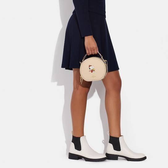 COACH X PEANUTS CANTEEN CROSSBODY WITH SNOOPY PRESENT MOTIF (CE845,CF290) กระเป๋าสะพายข้างทรงกลมไซส์มินิ มีหูจับ วัสหนังแท้ ด้านหน้าโดดเด่นด้วยรูปการ์ตูนSnoopy