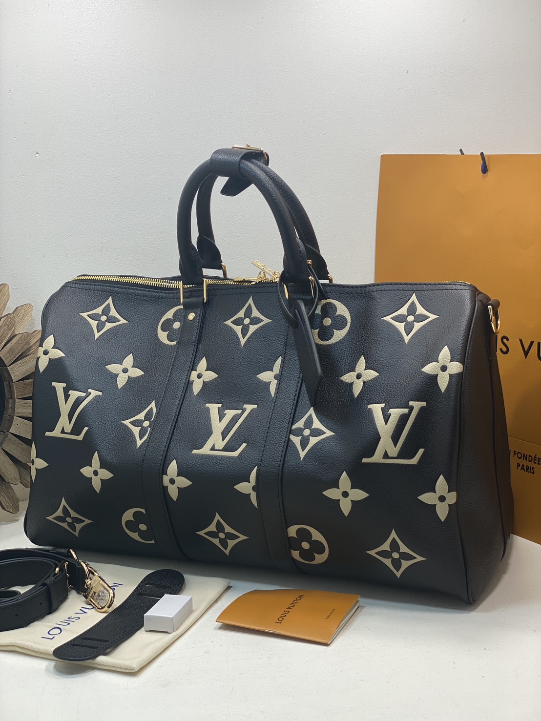 TOP ORI หนังแท้ | LV Keepall Bandoulière 45 bag กระเป๋าสะพายใบใหญ่ หนัง Empreinte ลาย Monogram Flower และสัญลักษณ์ LV ขนาดโอเวอร์ไซส์โทนสีอ่อน หนังโทนสีกลมกลืนกันแมตช์กับฮาร์ดแวร์สีทองบริเวณแถบด้านข้าง