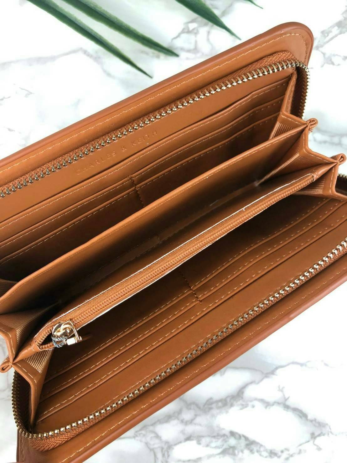 CHARLES & KEITH CLASSIC ZIP AROUND WALLET กระเป๋าเงินใบยาวซิปรอบ มีสายคล้องมีสีเข้ากระเป๋า 1 เส้น ใช้งานง่ายมากๆ คล้องมือก็เก๋ ด้านหน้าปั๊มโลโก้แบรนด์ เปิดปิดด้วยซิปรอบ ที่สายคล้องมือแต่งหมุดสีสวยเด่น ถอดสายได้ จุบัตรได้ 12 ใบ มีช่องซิปใส่เหรียญและช่องใส่