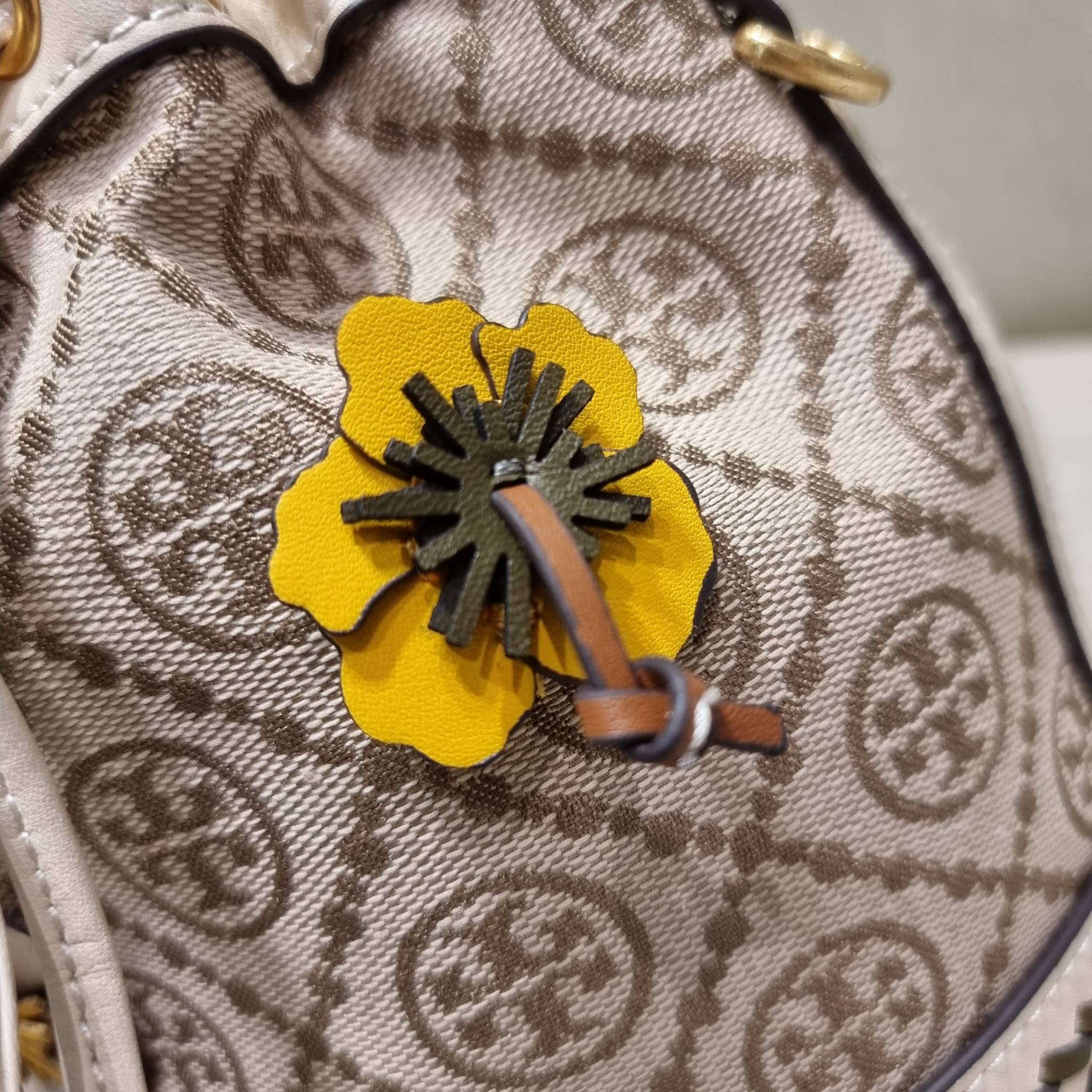 TORY BURCH MINI T MONOGRAM FLORAL BUCKET BAG คอลเลคชั่นใหม่ พร้อมเสิร์ฟความสวยให้ถึงบ้าน!! กระเป๋าบัคเก็ตทรงยอดนิยม ไซส์มินิ ดีไซน์ใหม่ล่าสุด สไตล์งานคราฟ มีลูกเล่นประดับดอกไม้กับตัวกระเป๋า และตัวรูดสาย วัสดุผ้า jacquard ตัดสลับหนังแท้ หูจับและขอบกระเป๋าต