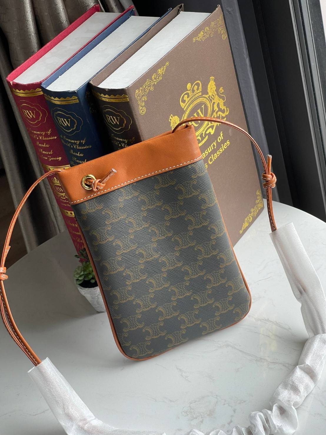 Celine Triomphe Pouch Crossbody Bag / Celine Phone Bag ในวันที่ต้องการความคล่องตัว เราสามารถหยิบกระเป๋าใส่โทรศัพท์ประเภทนี้เพื่อใส่เพียงแค่โทรศัพท์ เงิน และของสำคัญชิ้นเล็ก ๆ ได้เลย โดยไม่ต้องพกกระเป๋าใบใหญ่ ๆ ไปให้เกะกะ แถมยังดูเป็นแฟชั่นที่ทันสมัยอีกด้ว