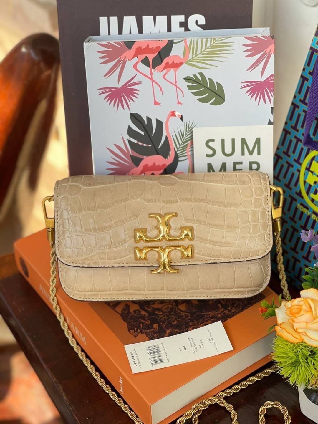 Tory Burch Eleanor Crocodile-Embossed Phone Crossbody Bag จุดเด่นของรุ่นนี้คือดีไซน์ออกมาในสไตล์คลาสสิกที่มาพร้อมกับฮาร์ดแวร์ที่ทำจากวัสดุทองเหลืองและสายสะพายโซ่เกลียวสีทอง ซึ่งการออกแบบได้รับแรงบันดาลใจมาจากเครื่องประดับ รูปทรงกะทัดรัดจึงสามารถสะพายใช้งา