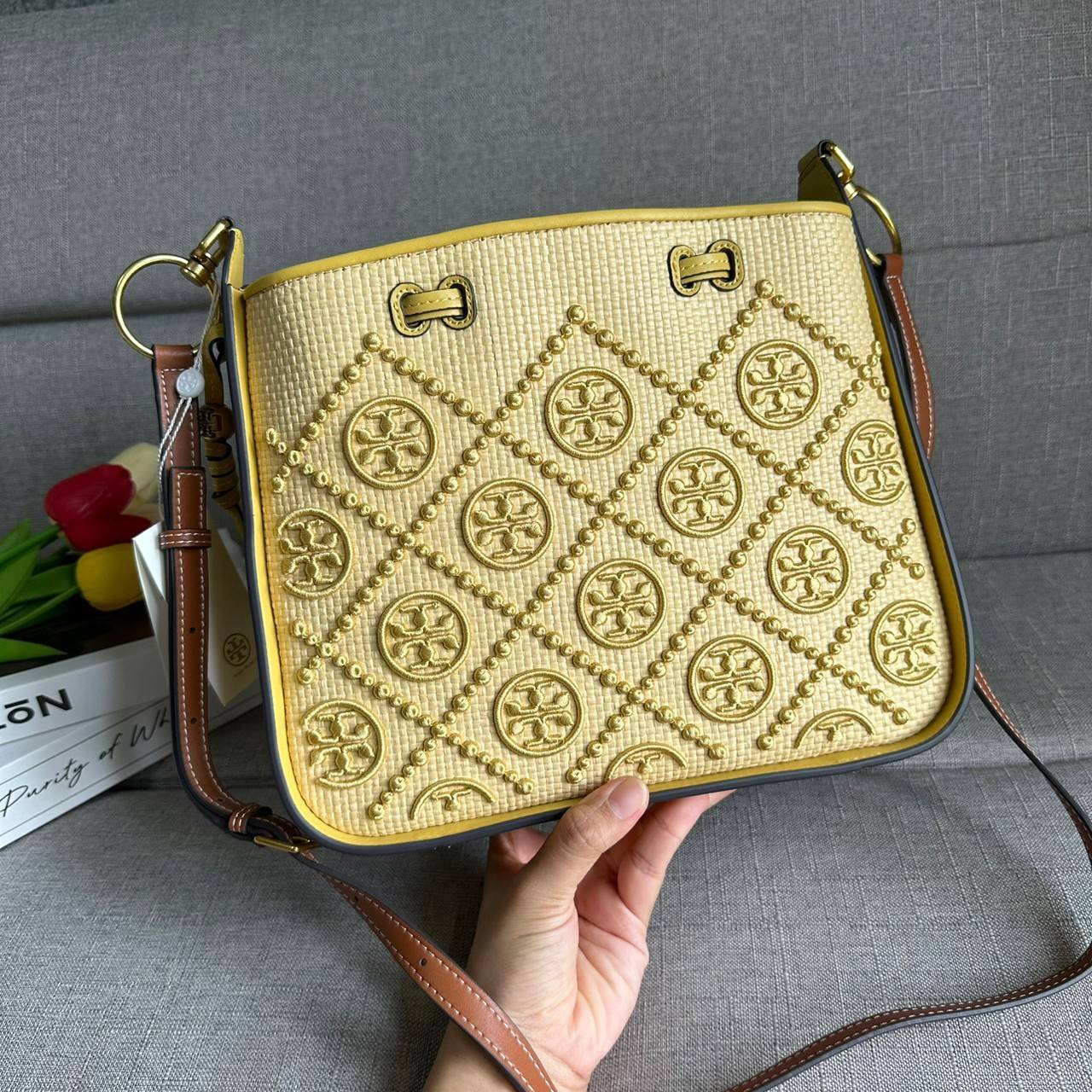 TORY BURCH T Monogram Straw Bell Bag กระเป๋าสะพายข้างรุ่นคลาสสิกที่ได้แรงบันดาลใจจากการควิลท์แบบดั้งเดิมของเพนซิลเวเนีย คอลเลกชันบ่งบอกถึงความมีสไตล์เหนือกาลเวลา รูปทรงเรียวโดดเด่น ปักทอลายแบรนด์อย่างสวยงาม เปิด ปิดด้วยเชือกรูด ด้านในช่องโล่งกว้าง ซับในผ้