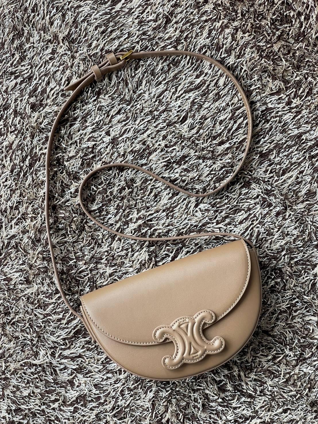 CELINE BESACE CUIR TRIOMPHE IN SMOOTH กระเป๋ารุ่นนี้นำเสนอในรูปทรงฮาล์ฟมูนที่ตอนนี้กำลังงมาแรง เปิดด้วยกระดุมแป๊กเพื่อเผยให้เห็นช่องภายในที่กว้างขวางและกระเป๋าด้านในแบบแบน คุณสมบัติที่โดดเด่นอีกอย่างของกระเป๋าอยู่ที่โลโก้ขนาดใหญ่ รูปทรงสะดุดตา สามารถสะพาย