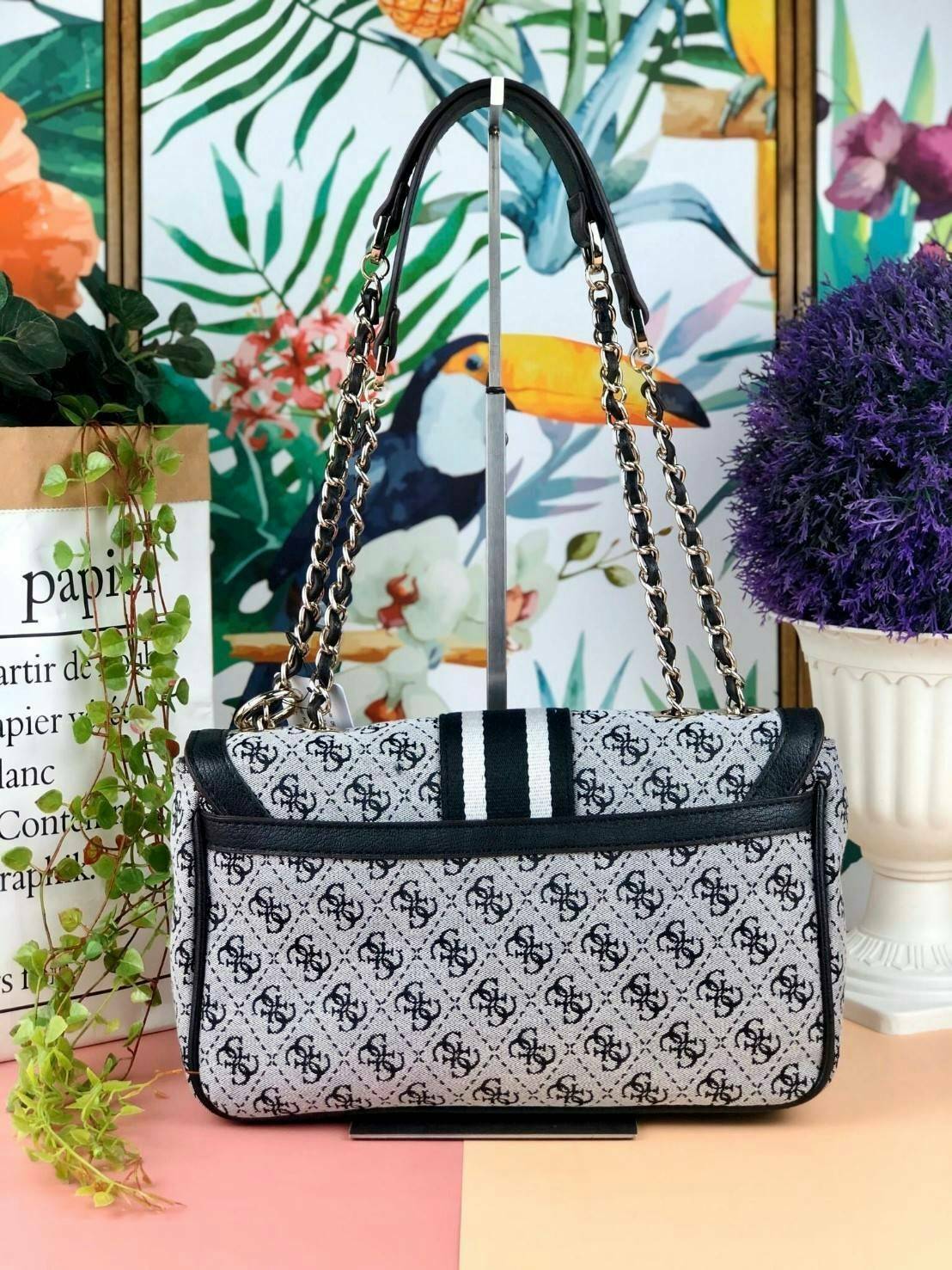 Guess Logo city handbag กระเป๋าสะพายไหล่ ตัวกระเป๋าเป็นผ้าลาย signature ของแบรนด์ ตัดกับหนังที่ตัวขอบกระเป๋า มาพร้อมพวงกุญแจโลโก้แบรนด์ ด้านหน้ามีโลโก้แบรนด์ ด้านหลังมีช่องใส่โทรศัพท์/บัตรได้ เปิดปิดแบบกระดุมแม่เหล็กซ้าย-ขวา ด้านในมีช่องซิป เล็ก 1 ช่อง แล