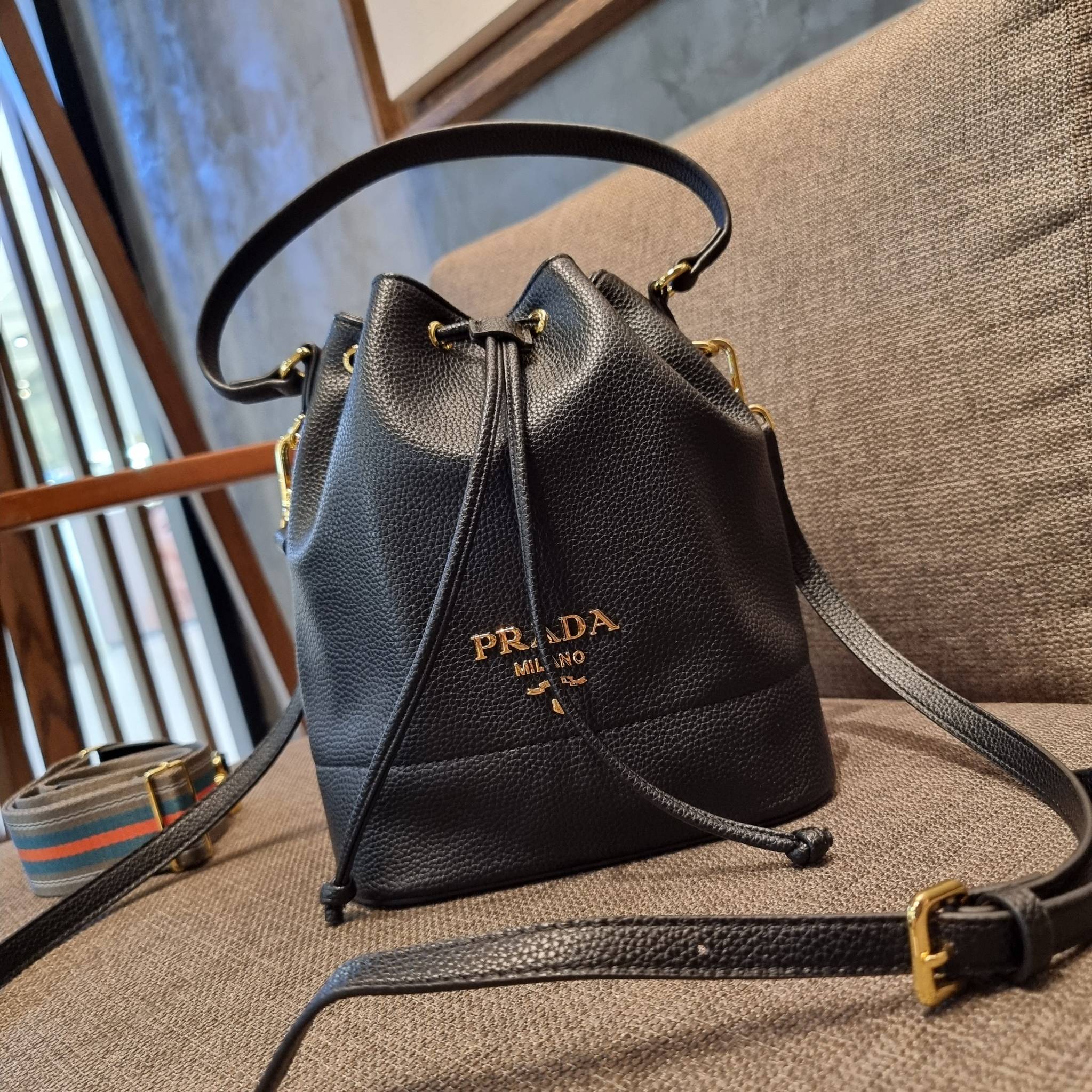 Prada leather bucket bag กระเป๋าสะพายทรงขนมจีบ ดีไซน์เรียบ แต่หรู น่าใช้มากๆ หนังสวยมาก วัสดุหนัง pepble สัมผัสนิ่มมือ ตกแต่งโลโก้สีทองตัดหนังดำ คือเลิศ!! ปากกระเป๋ารูดเปิดปิดได้ สะดวกใช้งาน ภายในโล่งกว้าง จุของได้เยอะ ไม่ธรรมดาเลย พิเศษ!! นอกจากสายคล้องใ