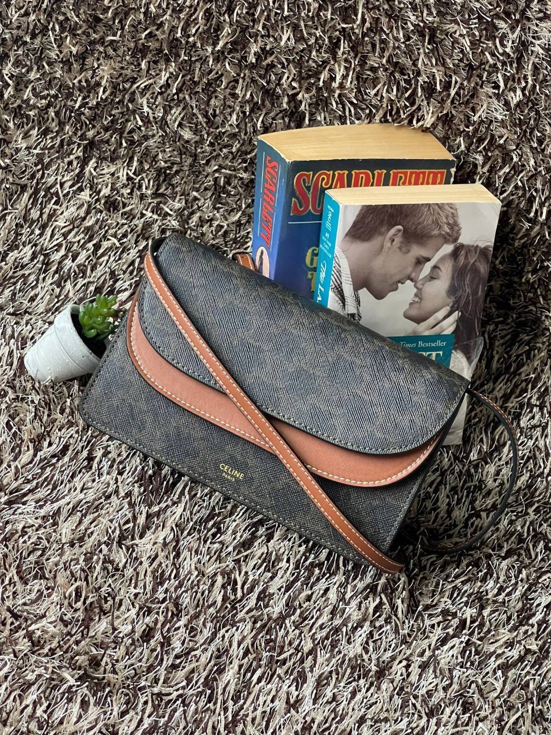 CELINE WALLET ON STRAP IN TRIOMPHE CANVAS กระเป๋าสะพายไหล่สุดเก๋ใบนี้ผลิตจากผ้าใบเคลือบอย่างดีพร้อมขอบหนังสีน้ำตาล กระเป๋ามีสายสะพายหนังสีน้ำตาลพร้อมฮาร์ดแวร์สีทอง ถอดสายออกเพื่อเป็นกระเป๋าถือทรงคลัชท์เปลี่ยนลุคช์ ลวดลายtriomphe ความเป็นแบรนด์ CELINE ได้อ