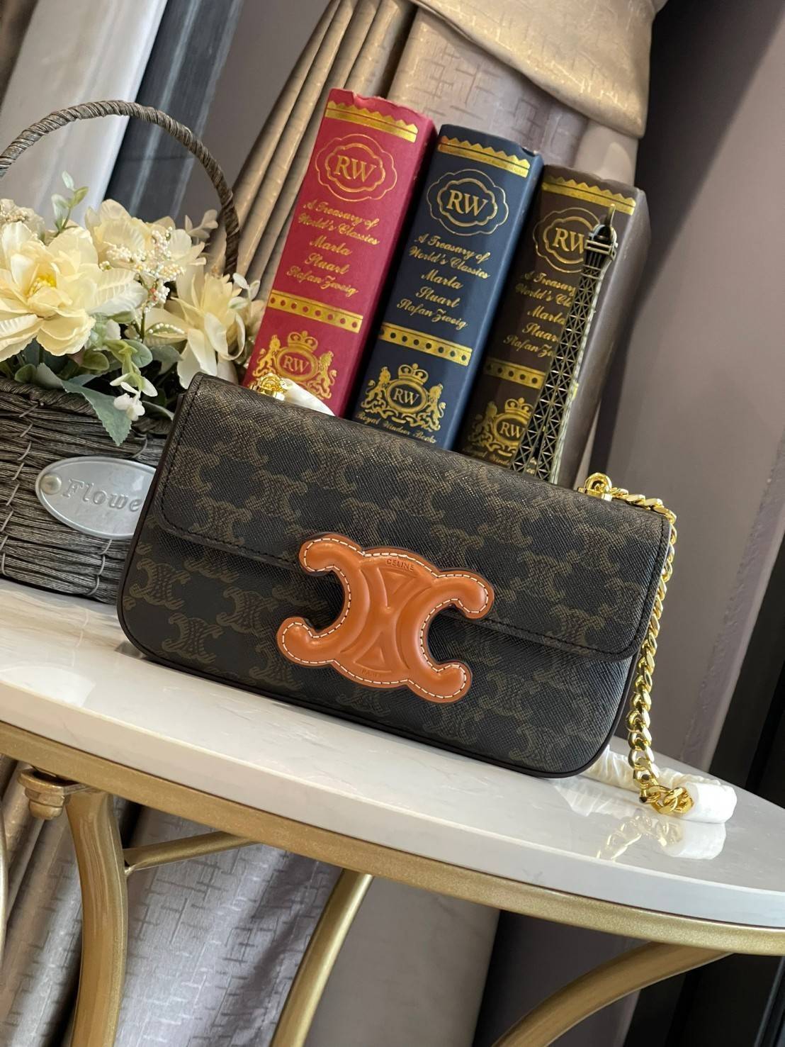 Celine Chain Shoulder Bag Cuir Triompe In Triompe เป็นกระเป๋าถูกประดิษฐ์ขึ้นในรูปทรงมินิมอล นับว่าเป็นกระเป๋าอีกหนึ่งรุ่นในซีรีส์ Triomphe ที่ได้รับความนิยมอย่างมาก โดยเป็นกระเป๋าสะพายไหล่ทรงสี่เหลี่ยมผืนผ้าที่อัดแน่นไปด้วยกลิ่นอายความคลาสสิกตามแบบฉบับของ