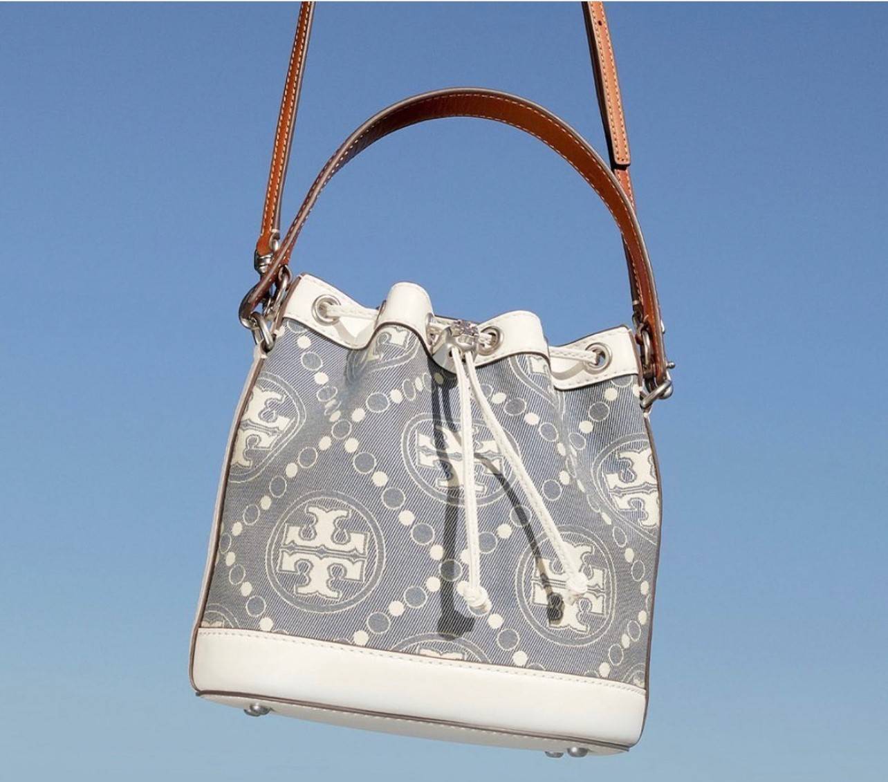 TORY BURCH T Monogram Denim Bucket Bag MEDIUM คอลเลคชั่นใหม่ รูปแบบคลาสสิค พกพาความหรูหราไปได้ทุกที่ด้วยกระเป๋าทรง Bucket ขนาดกลางและปิดด้วยเชือกรูดพร้อมโลโก้แวววาว วัสดุผ้าเดนิมแจ็คการ์ด ตัดขอบหนังแท้
