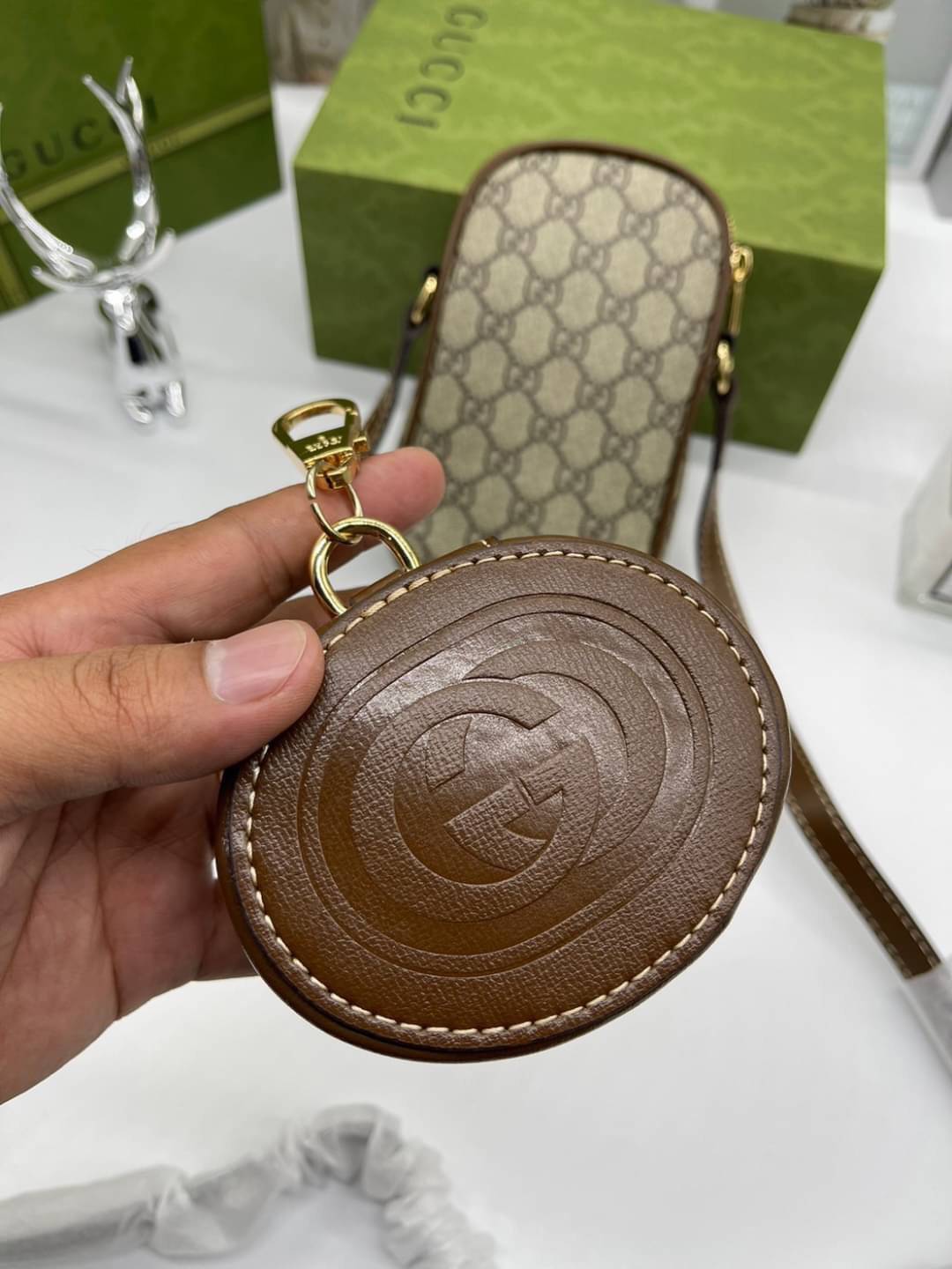 GUCCI Mini bag with Interlocking G / Gucci phone bag เกรดออริจินอล กระเป๋ามินิรังสรรค์จากผ้าแคนวาส Supreme ลายโมโนแกรมของแบรนด์สีเบจและสีน้ำตาลอีโบนี สัญลักษณ์ GG สไตล์นี้มอบความรู้สึกร่วมสมัยพร้อมกระเป๋าใส่ Apple AirPods ที่สามารถถอดออกได้