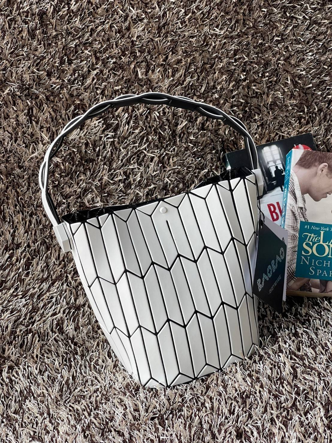 Small : BAO BAO ISSEY MIYAKE SMALL BUCKET เป็นกระเป๋าบัคเก็ตขนาดเล็กสามารถใช้ใส่กระเป๋าสตางค์และโทรศัพท์มือถือได้ ซีรีย์ใหม่นี้มีจุดเด่นที่แผ่นรูปทรงสี่เหลี่ยมด้านขนานในแนวตั้ง เกิดเป็นรูปทรงสามมิติซึ่งแตกต่างไปจากรูปทรงที่เกิดขึ้นจากแผ่นสามเหลี่ยม หูหิ้ว