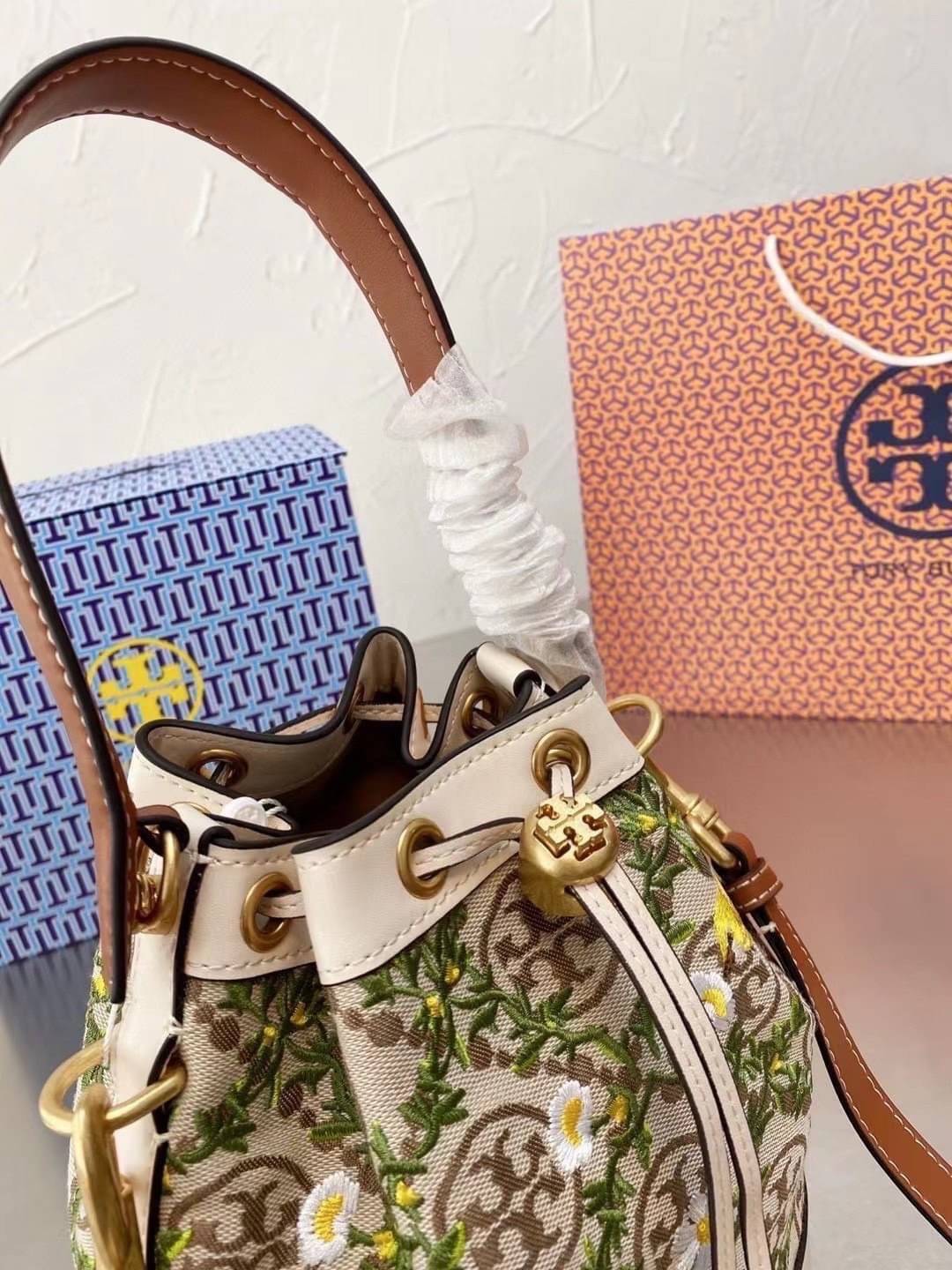 TORY BURCH T MONOGRAM JACQUARD EMBROIDERED BUCKET BAG ครั้งแรกกับโมโนแกรม ที่ได้รับแรงบันดาลใจมาจากโลโก้สุดคลาสสิก กลับมาอีกครั้งในรูปแบบของ ลวดลาย T Monogram ที่ผสมผสานความร่วมสมัยเข้ากับความเป็นเอกลักษณ์ของแบรนด์เข้าไว้ด้วยกัน โดยเป็นการนำเอาลวดลาย T Mo