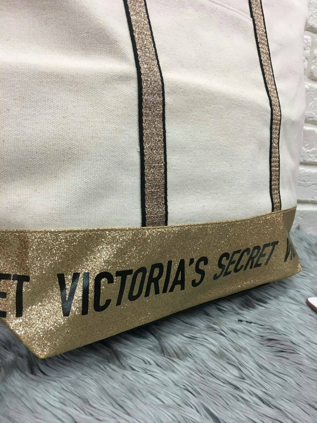 Victoria's Secret Canvas Tote Bag กระเป๋าสะพายวัสดุแคสวาสสีครีม ด้านล่างเป็นกลิตเตอร์ สกรีนชื่อแบรนด์ ฐานกระเป๋าเป็นหนัง ด้านหน้ามีช่องเล็กไว้ใส่ของได้ เปิดปิดด้วยซิป ซับในลายแบรนด์ มีช่องซิปเล็กแยกใส่ของ1ช่อง จุของได้เยอะมาก