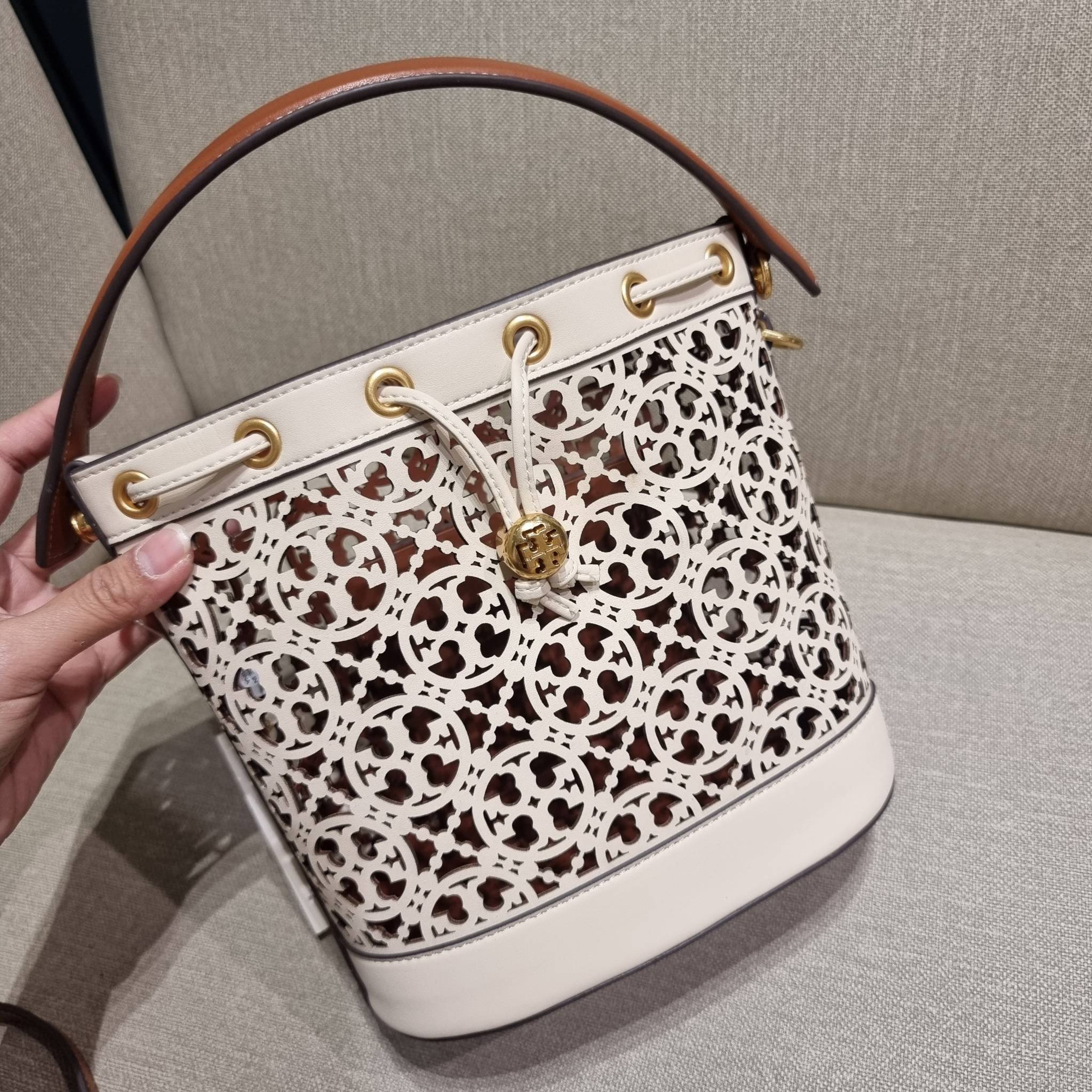TORY BURCH T MONOGRAM LASER-CUT BUCKET BAG ใจบางที่สุดกับคอลเลคชั่นนี้ กับกระเป๋าสะพายทรงบัคเก็ต รุ่นชูโรงสุดฮิต ที่เพิ่มดีเทลความแพงด้วยการฉลุลวดลายโมโนแกรมรอบใบ ถักทอเป็นเส้นลายสานที่สวยงามมาก งานฝีมือจริงๆ วัสดุหนัง cowhide รูดเปิด-ปิดด้วยเส้นหนัง มาพร