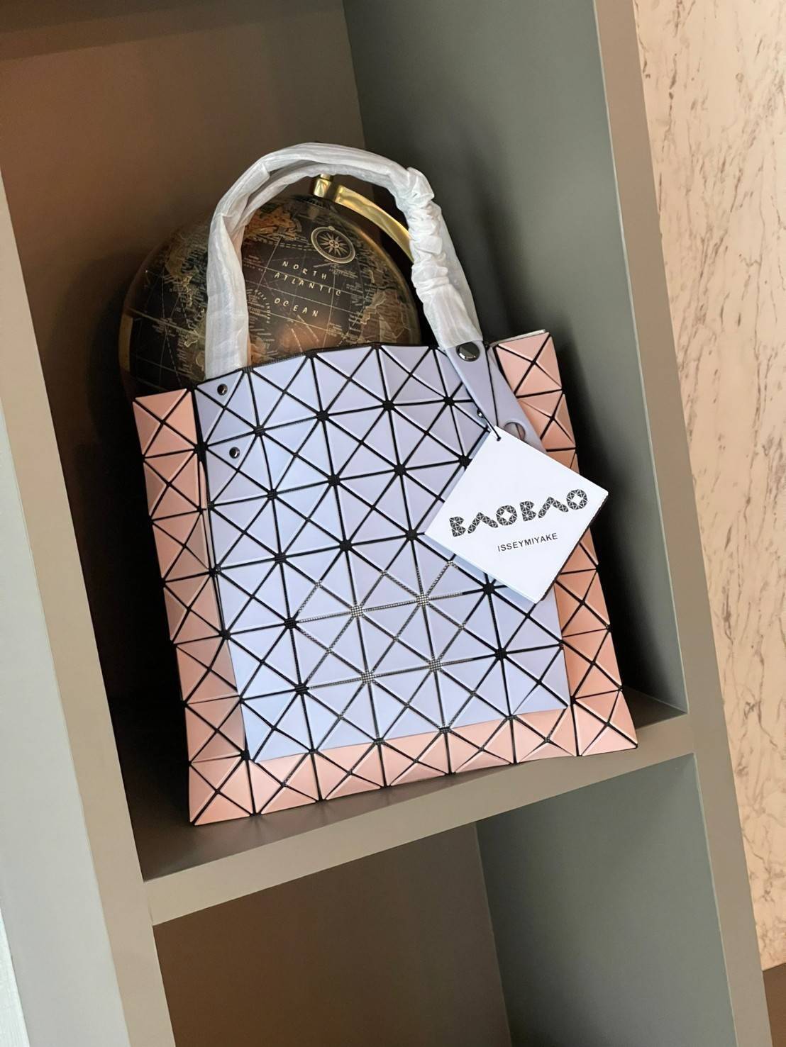 Baobao Issey Miyake Prism Kangaroo tote bag กระเป๋าถือทรงโท้ทที่ประดิษฐ์ขึ้นอย่างเชี่ยวชาญในญี่ปุ่น มาพร้อมแผงเรขาคณิตสำหรับการออกแบบที่ได้รับแรงบันดาลใจจากกระดาษพับ ซิลลูเอทอันเป็นเอกลักษณ์นี้ปิดท้ายด้วยสายรัดแบบอสมมาตร มีการพัฒนาโครงสร้างทรงสามเหลี่ยมเพ