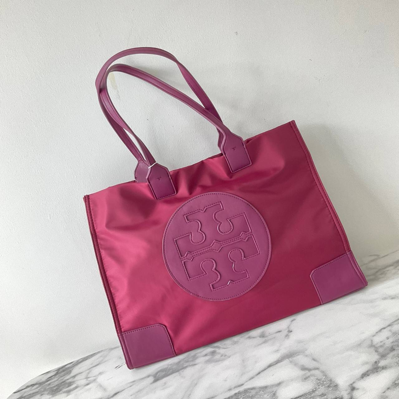 กระเป๋าทรงโท้ทใบใหญ่ TORY BURCH ELLA TOTE BAG วัสดุ NYLON ทั้งใบตัดด้วยหนังสีดำ แต่งโลโก้แบรนด์ด้านหน้า ด้านข้างมีกระดุม สามารถขยายทรงได้ ด้านในเปิดปิดด้วยกระดุมแม่เหล็กฝัง ช่องกว้างหลักหนึ่งช่องและช่องซิปอีกช่อง สามารถใส่แล็ปท็อปได้สบาย ใบใหญ่เว่อวัง ไอเ