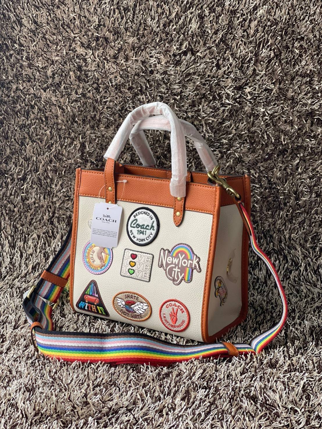 COACH FIELD TOTE 22 WITH PATCHES CA138 ส่วนหนึ่งจาก Coach Pride Collection ซึ่งเป็นการเฉลิมฉลองความเท่าเทียม ความหลากหลาย และการแสดงออกถึงตัวตนที่แท้จริงภายในชุมชน LGBTQIA+ ในเดือนนี้และทุกเดือน ตั้งแต่วันธรรมดาที่วุ่นวายไปจนถึงวันหยุดสุดสัปดาห์ที่เต็มไปด