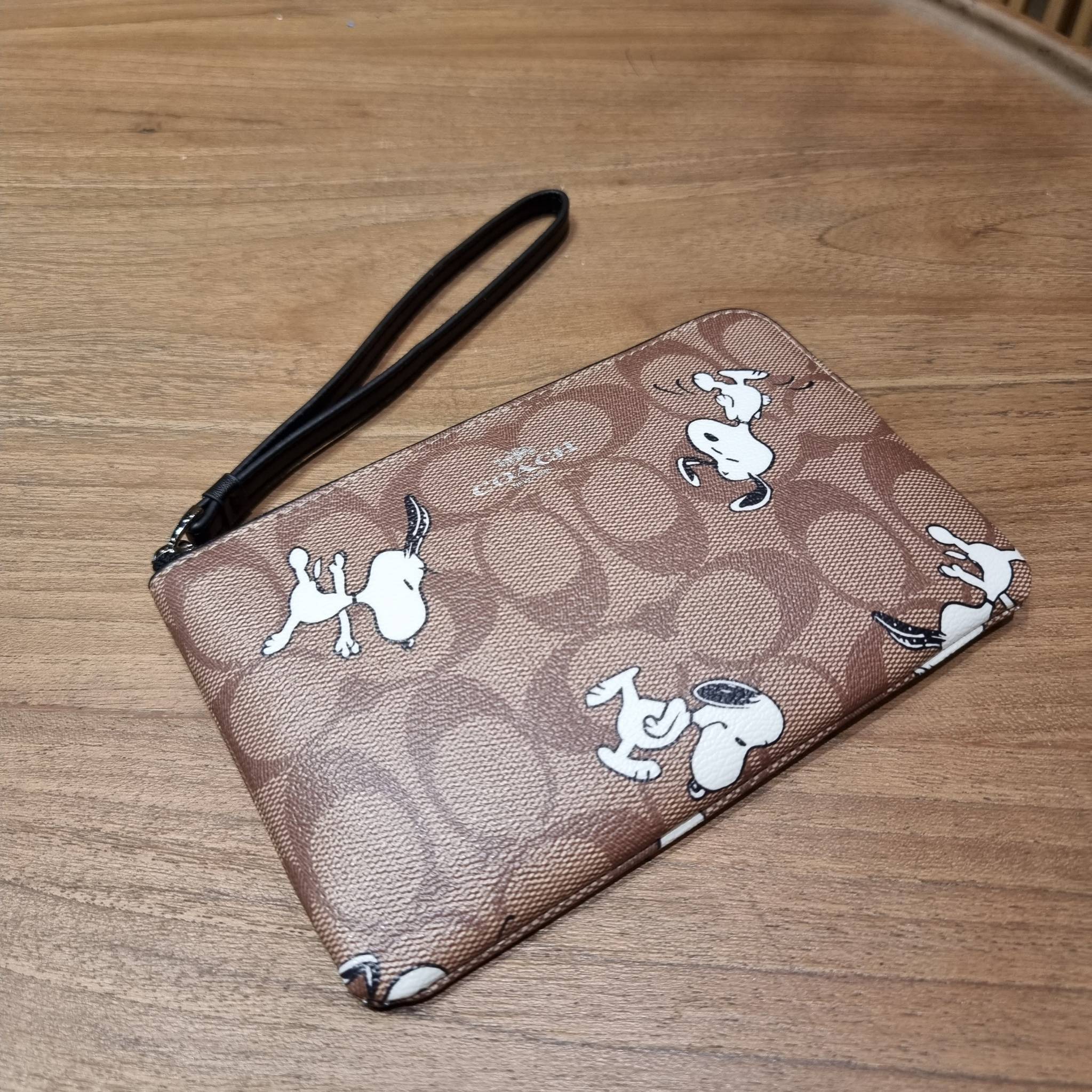 COACH C4589 COACH x PEANUTS CORNER ZIP WRISTLET IN SIGNATURE CANVAS WITH SNOOPY PRINT เหล่าผองเพื่อนและสนูปพีมาแล้วจ้า คอลเลคชั่นสุดน่ารักที่ฮอตไม่มีตก กระเป๋าคล้องมือ ขนาดเหมาะพกพากำลังเหมาะ วัสดุหนังแคนวาสเคลือบลาย ภายในเป็นช่องโล่ง ใส่ธนบัตร หรือใส่บัต