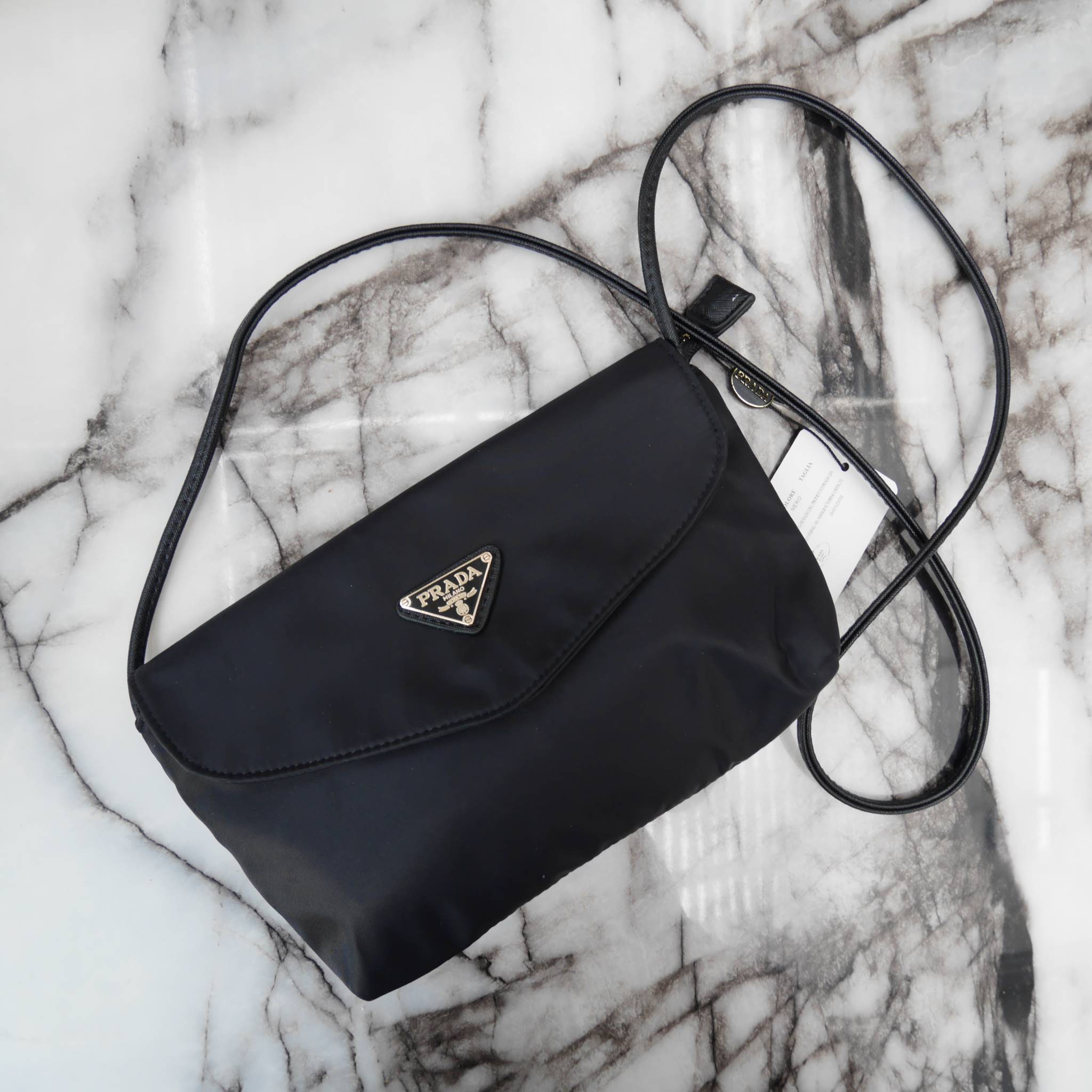 Best Seller! จากงานพรีเมี่ยมกิ้ฟ จากเคาเตอร์ต่างประเทศ จากแบรนด์ PRADA ค่า เป็น กระเป๋าผ้าไนล่อน ตามแบบฉบับของแบรนด์เลย ใบนี้มีสายยาวให้คะ เลิศมาก สะพายเป็น shoulder bag ได้เลย ขนาดกำลังดีคะ ตัวกระเป๋าเบามาก ใส่มือถือได้ทุกรุ่น ใช้แล้วสวยมากๆ อะไหล่ทองหรู