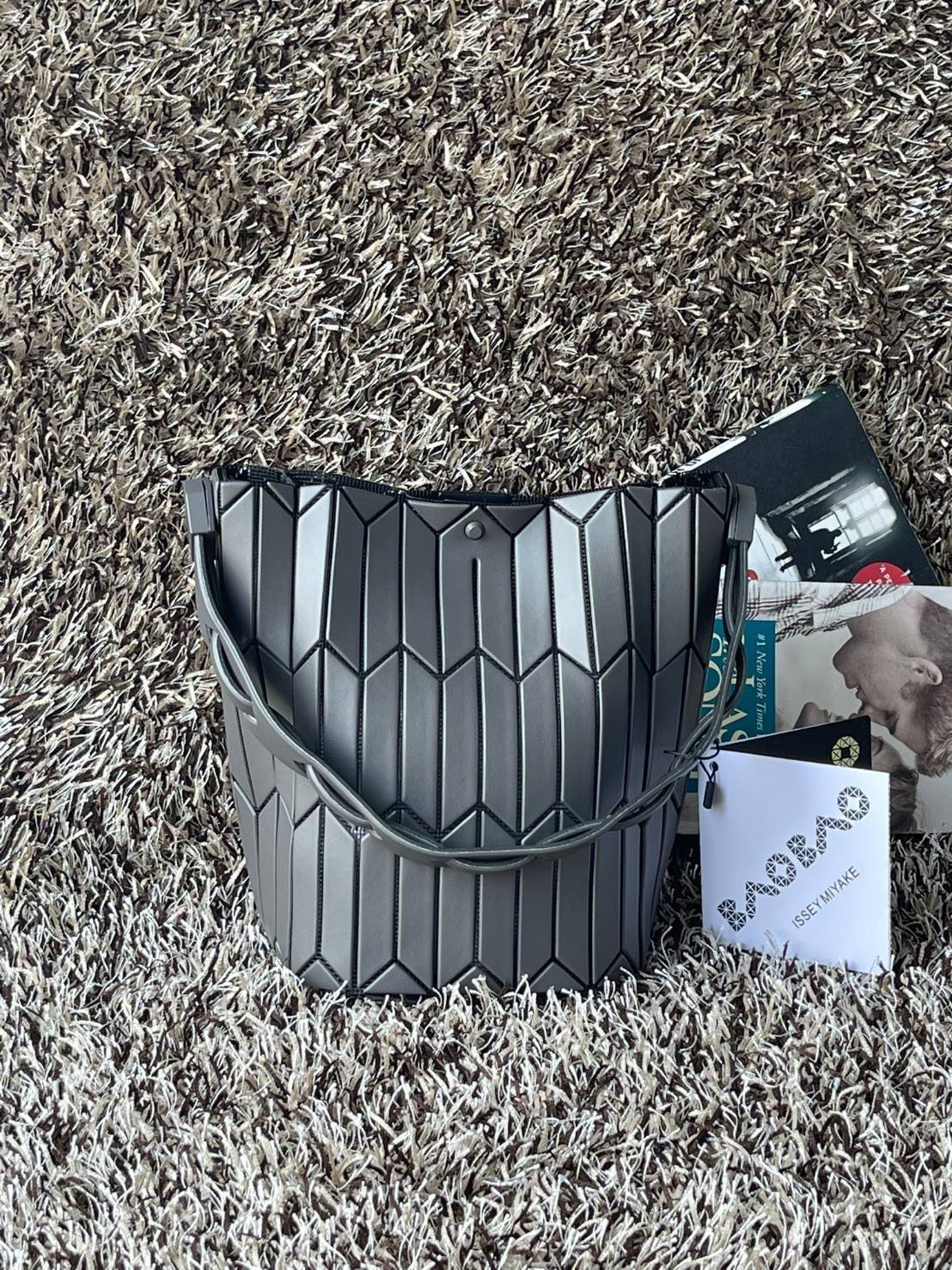 Small : BAO BAO ISSEY MIYAKE SMALL BUCKET เป็นกระเป๋าบัคเก็ตขนาดเล็กสามารถใช้ใส่กระเป๋าสตางค์และโทรศัพท์มือถือได้ ซีรีย์ใหม่นี้มีจุดเด่นที่แผ่นรูปทรงสี่เหลี่ยมด้านขนานในแนวตั้ง เกิดเป็นรูปทรงสามมิติซึ่งแตกต่างไปจากรูปทรงที่เกิดขึ้นจากแผ่นสามเหลี่ยม หูหิ้ว