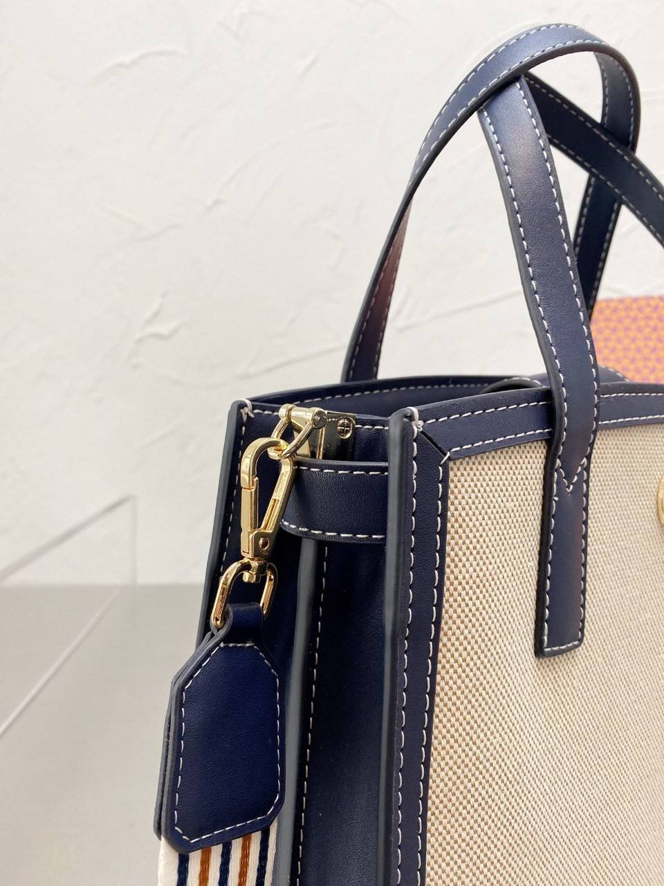 TORY BUTCH SMALL WALKER CANVAS กระเป๋าถือ สะพาย ดีไซสน์สวย เป็นเอกลักษณ์ วันดุผ้า CANVAS ด้านนอกประดับโลโก้แบรนด์ด้านหน้า ตัดด้วยหนังแท้รอบใบ ด้านในเปิดปิดด้วยหนังคาดกระดุมแม่เหล็ก แบ่งของใส่ของเป็นสองช่องใหญ่ พร้อมข่องซิปกลาง สามารถใส่ไอแพด กระเป๋าสตางค์