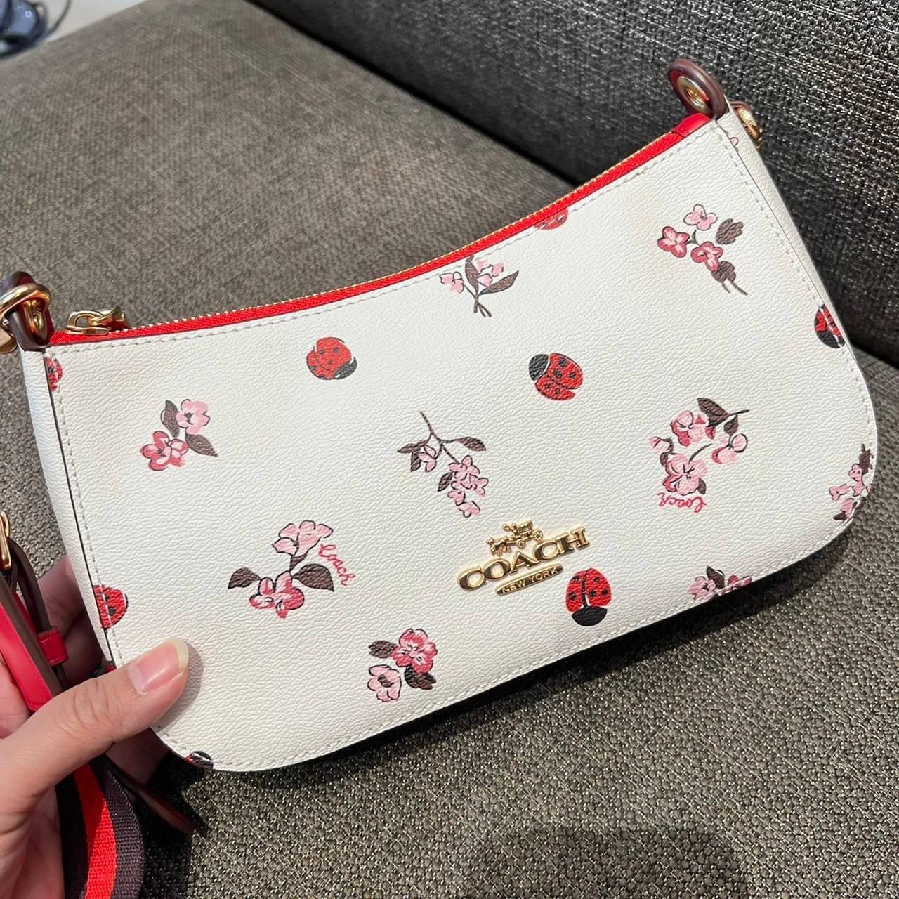 COACH C7973 JES BAGUETTE WITH LADYBUG FLORAL PRINT คอลเลคชั่นใหม่ล่าสุด พร้อมเสิร์ฟความสวยถึงบ้านเช่นเคย!! กระเป๋าสะพายทรงบาแกตต์ ดีไซน์ย้อนยุค ที่แอบแฝงความเรียบหรูดูแพงอยู่ในตัว โดดเด่นด้วยสายสะพายเส้นใหญ่ โทนสีคอนทราส ทำให้ไอเท็มนี้ดูมีลูกเล่นมากขึ้น ว