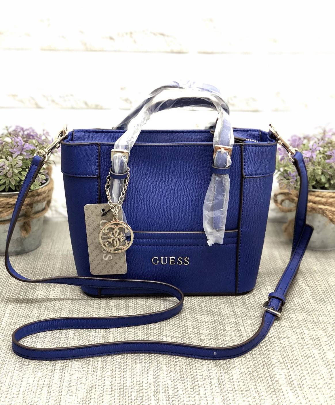 GUESS SAFFIANO MINI CROSS BODY BAG กระเป๋าถือหรือสะพายรุ่นยอดนิยมจาก GUESS หนัง Saffiano สวยอยู่ทรงสไตล์ PRADA ขนาดกำลังดีน้ำหนักเบา ด้านหน้าประดับโลโก้แบรนด์ พร้อมพวงกุญแจโลโก้แบรนด์ห้อยที่หูกระเป๋าสามารถถอดเเยกใช้ได้ เปิดปิดด้วยซิปสะดวกใช้ ภายในมีโลโก้ 