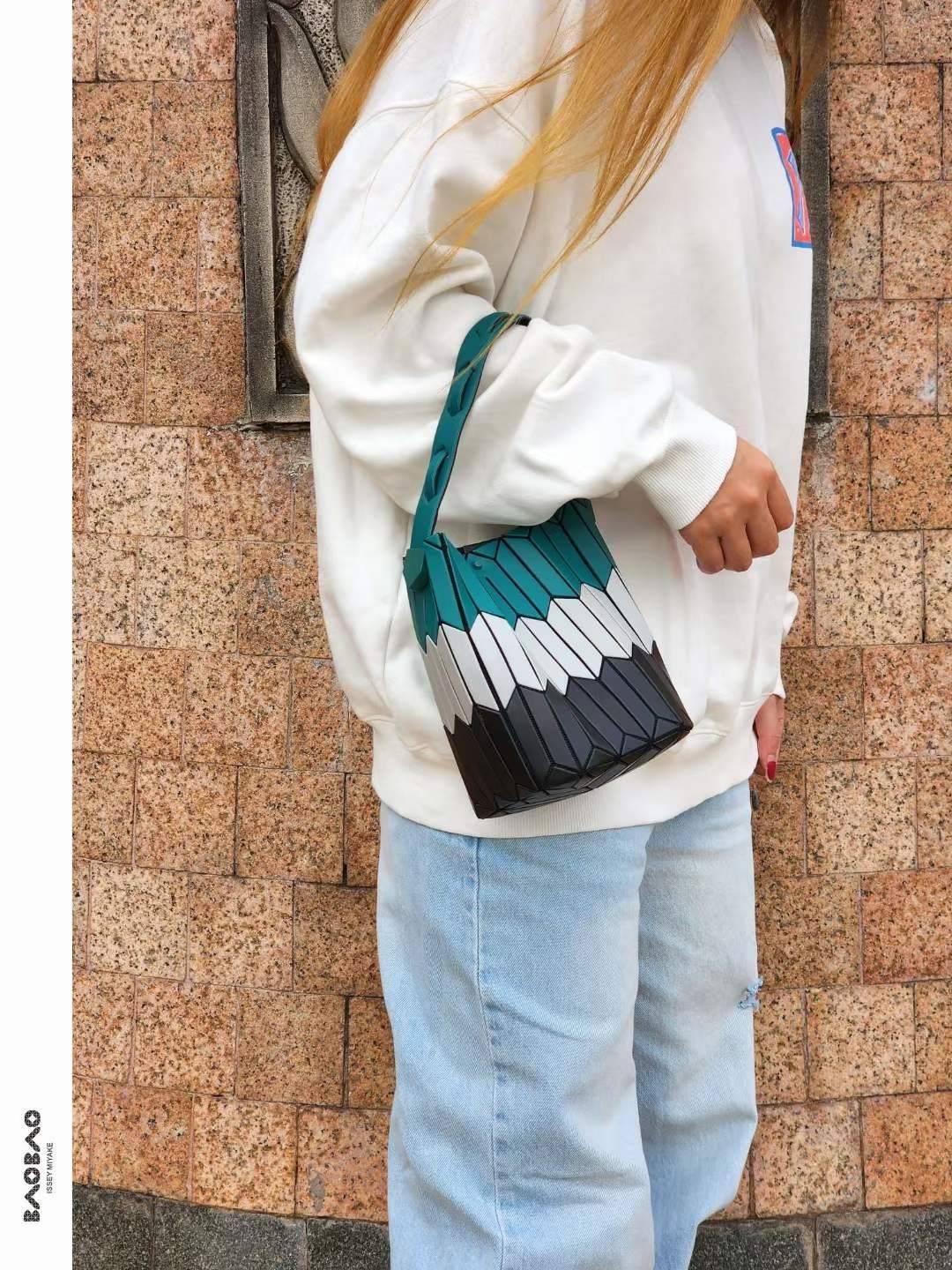 Small : BAO BAO ISSEY MIYAKE SMALL BUCKET เป็นกระเป๋าบัคเก็ตขนาดเล็กสามารถใช้ใส่กระเป๋าสตางค์และโทรศัพท์มือถือได้ ซีรีย์ใหม่นี้มีจุดเด่นที่แผ่นรูปทรงสี่เหลี่ยมด้านขนานในแนวตั้ง เกิดเป็นรูปทรงสามมิติซึ่งแตกต่างไปจากรูปทรงที่เกิดขึ้นจากแผ่นสามเหลี่ยม หูหิ้ว