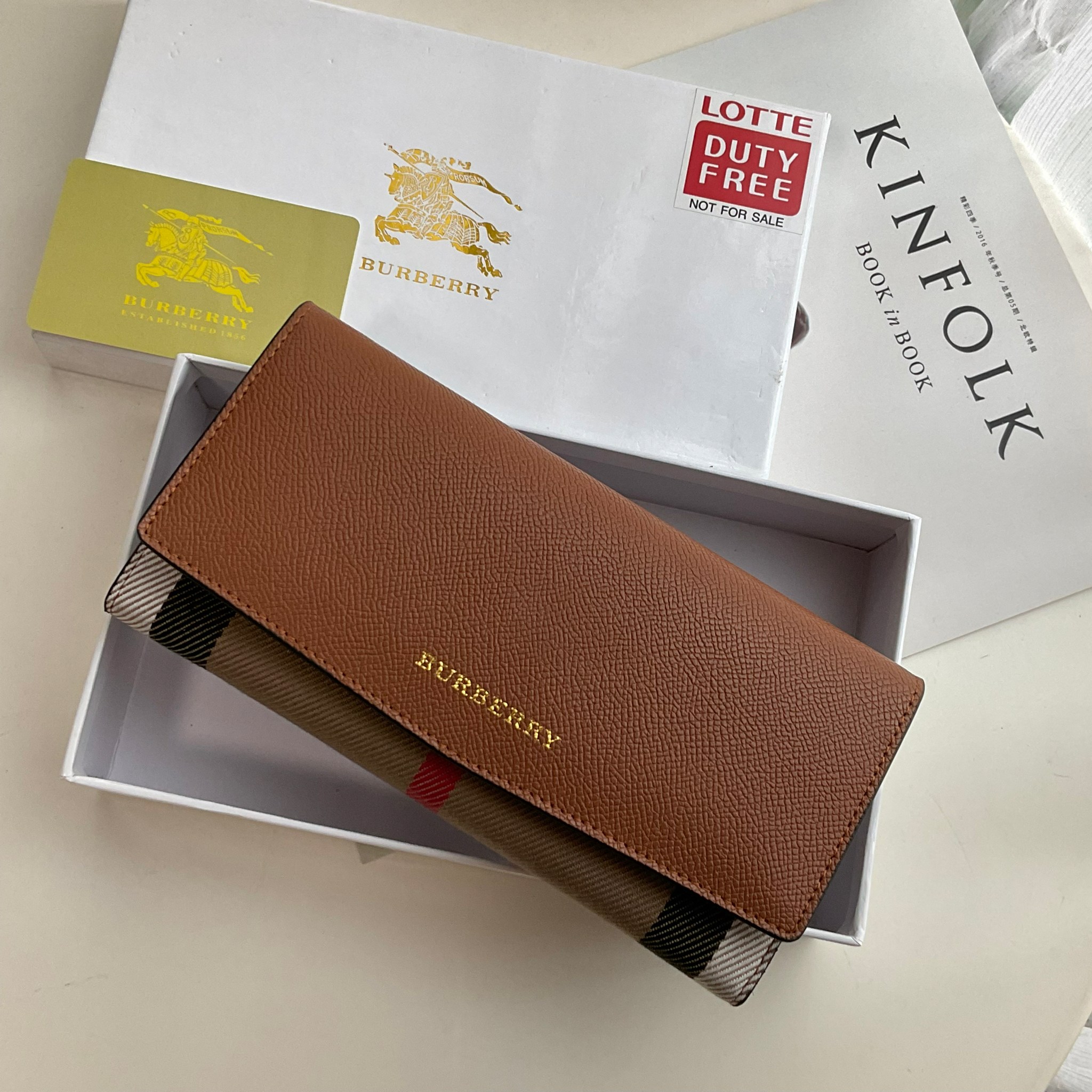 กระเป๋าสตางค์รับทรัพย์ ทรงหรู จากงาพรีเมี่ยมกิ๊ฟ Limited Edition จาก BURBERRY กระเป๋าสตางค์ใบยาวแบบพับกระดุม ทูโทนด้วยหนังแท้คาดผ้าลาย vintage ด้านในมีช่องใส่ธนบัตรยาวทั้งสองฝั่ง ช่องใส่บัตรได้อย่างน้อย 12 ช่อง และช่องเปิดด้วยซิปปั้มแบรนด์อะไหล่ทองสุดหรู 