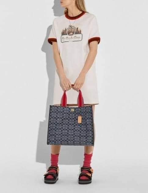 COACH Tote 34 In Signature Chambray หากคุณกำลังมองหากระเป๋าที่มีดีไซน์แปลกตา ไม่ค่อยเหมือนที่พบเห็นทั่วไป ต้องเป็นรุ่นนี้เลยค่ะ นอกจากจะผลิตจากผ้าแชมเบรย์ซึ่งมีน้ำหนักเบาแล้ว ยังให้สีสันคล้ายกับสียีนส์ สายสะพายและหูหิ้วสไตล์สปอร์ต ที่สำคัญยังมีหมุดปิดกระเ