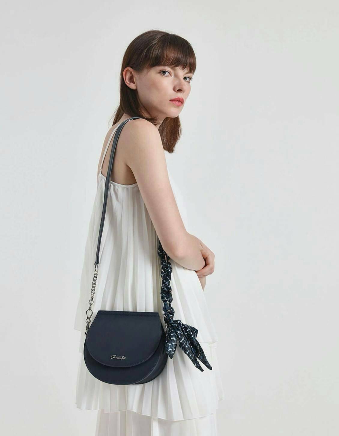 CHARLES & KEITH รุ่น LEATHER SATIN SCARF CROSSBODY BAG SL2-50150828 ราคาปกติช้อป ( ฿3,590.00 ) กระเป๋าถือ และ สะพาย ทรงโค้งมน หนังเรียบ ตั้งอยู่ทรง ด้านหน้าติดโลโก้แบรนด์ อะไหล่เงิน หูจับสายกระเป๋าร้อยเข้ากับห่วงเหล็กกลมๆ ด้วยผ้าลายสวยงามผูกเป็นโบว์เก๋ๆ ถ