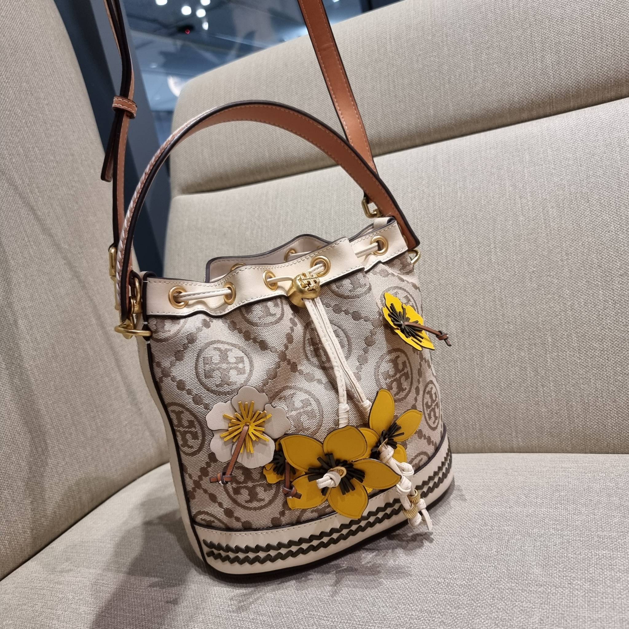 TORY BURCH T MONOGRAM FLORAL BUCKET BAG คอลเลคชั่นใหม่ พร้อมเสิร์ฟความสวยให้ถึงบ้าน!! กระเป๋าบัคเก็ตทรงยอดนิยม ดีไซน์ใหม่ล่าสุด สไตล์งานคราฟ มีลูกเล่นประดับดอกไม้กับตัวกระเป๋า และตัวรูดสาย วัสดุผ้า jacquard ตัดสลับหนังแท้ หูจับและขอบกระเป๋าตกแต่งลายสานสวย