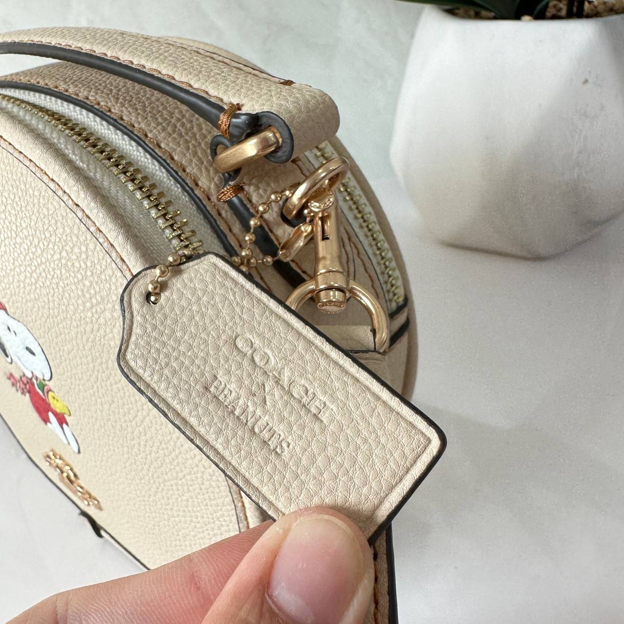 COACH X PEANUTS CANTEEN CROSSBODY WITH SNOOPY PRESENT MOTIF (CE845,CF290) กระเป๋าสะพายข้างทรงกลมไซส์มินิ มีหูจับ วัสหนังแท้ ด้านหน้าโดดเด่นด้วยรูปการ์ตูนSnoopy