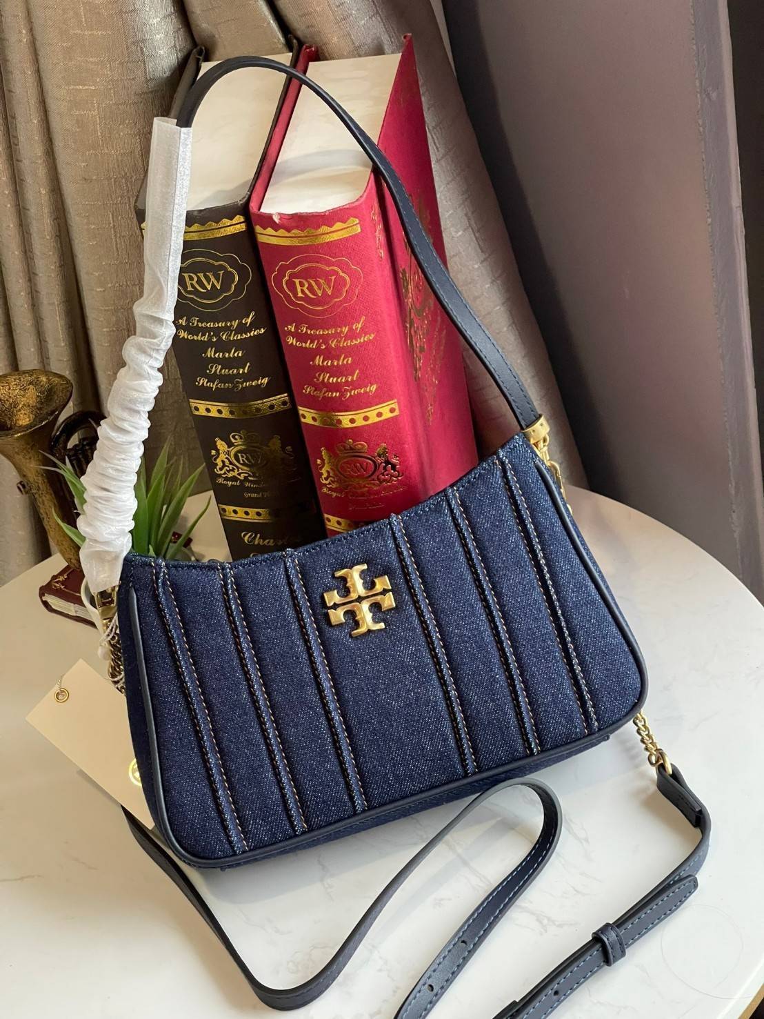 Tory burch Kira logo-plaque crossbody bag กระเป๋า Kira ของ Tory Burch เป็นส่วนหนึ่งของคอลเล็กชั่นที่โดดเด่น และมีหลายรุ่นด้วยกัน โดยมีป้ายโลโก้ Double T ของแบรนด์อยู่ตรงกลาง มีความเรียบง่ายแต่ยังคงความหรูหราโดดเด่นด้วยวัสดุบุผิว ป้ายโลโก้สีทอง สายสะพายโซ่