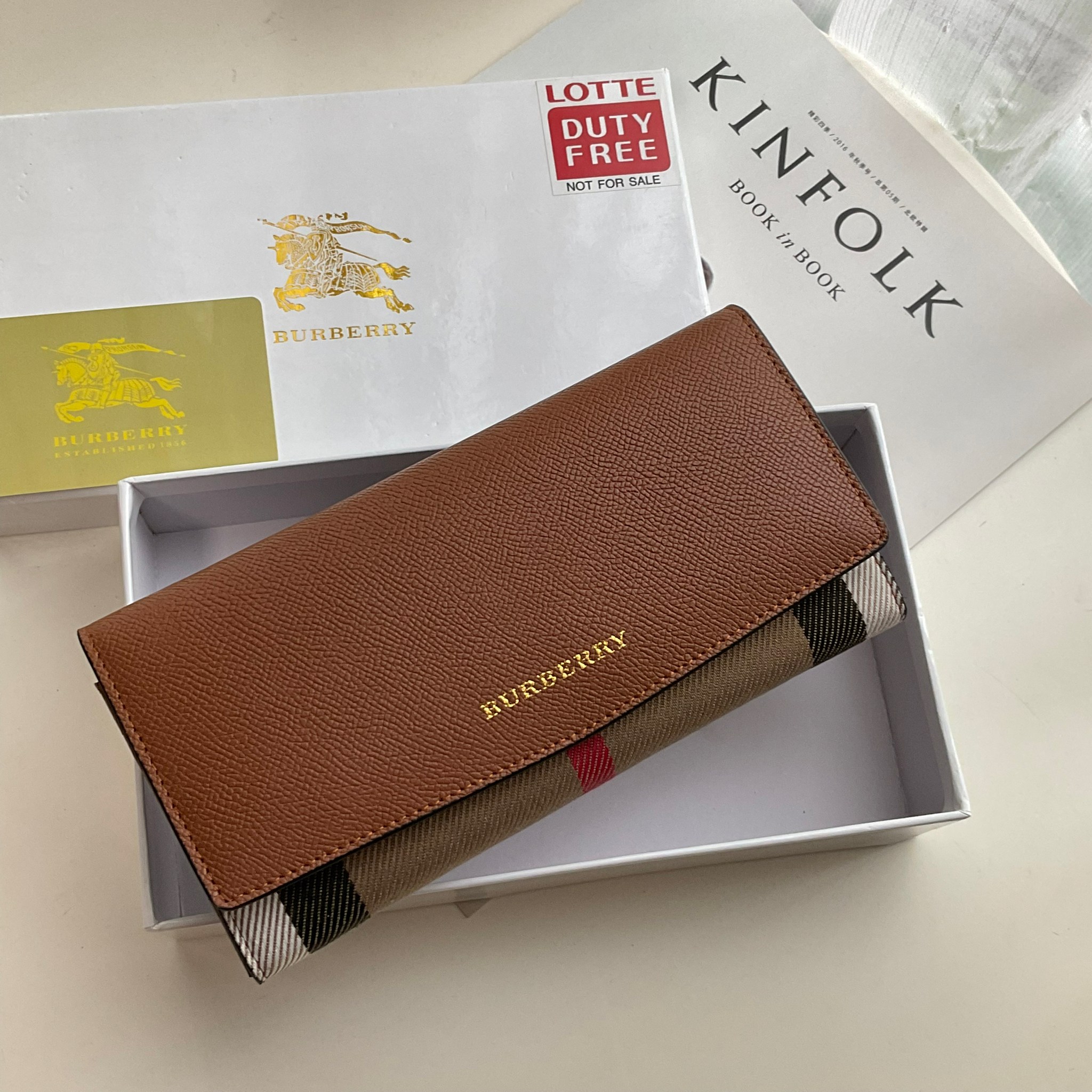 กระเป๋าสตางค์รับทรัพย์ ทรงหรู จากงาพรีเมี่ยมกิ๊ฟ Limited Edition จาก BURBERRY กระเป๋าสตางค์ใบยาวแบบพับกระดุม ทูโทนด้วยหนังแท้คาดผ้าลาย vintage ด้านในมีช่องใส่ธนบัตรยาวทั้งสองฝั่ง ช่องใส่บัตรได้อย่างน้อย 12 ช่อง และช่องเปิดด้วยซิปปั้มแบรนด์อะไหล่ทองสุดหรู 