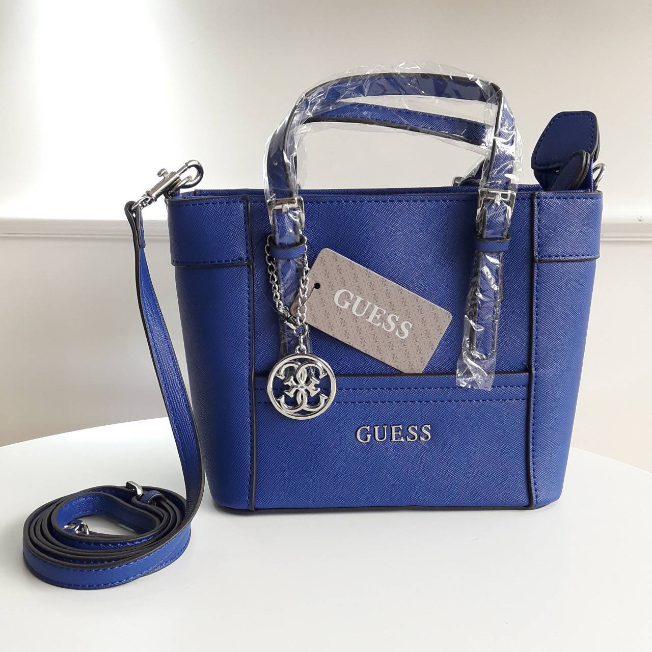 New! guess mini tote saffiano bag ลายหนัง Saffiano สวยอยู่ทรงสไตล์ PRADA ขนาดกำลังดีน้ำหนักเบา ด้านหน้าประดับโลโก้แบร์น พร้อมพวงกุญแจโลโก้แบรนด์ห้อยที่หูกระเป๋าสามารถถอดเเยกใช้ได้ เปิดปิดด้วยซิปสะดวกใช้ ภายในมีโลโก้ ช่องซิปและช่องเล็กใส่มือถือ ซับในพิมโลโ