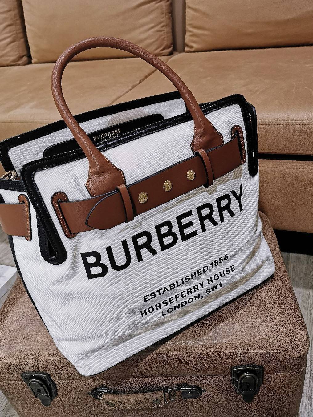 BURBERRY FRAGRANCES TOTE BAG อีกหนึ่งไอเท็มหายาก วัสดุ Canvas & Leather Calfskin ดีไซน์สวยมีเอกลักษณ์คาดด้วยสายหนังประดับกระดุมทองด้านหน้า หูจับหนังแท้จับถนัดมือ สายสะพายยาวหนังแท้ถอดได้ปรับระดับได้อะไหล่แบรนด์ ภายในโล่งกว้างมีช่องใส่ของใส่เอกสารA4 กระเป๋