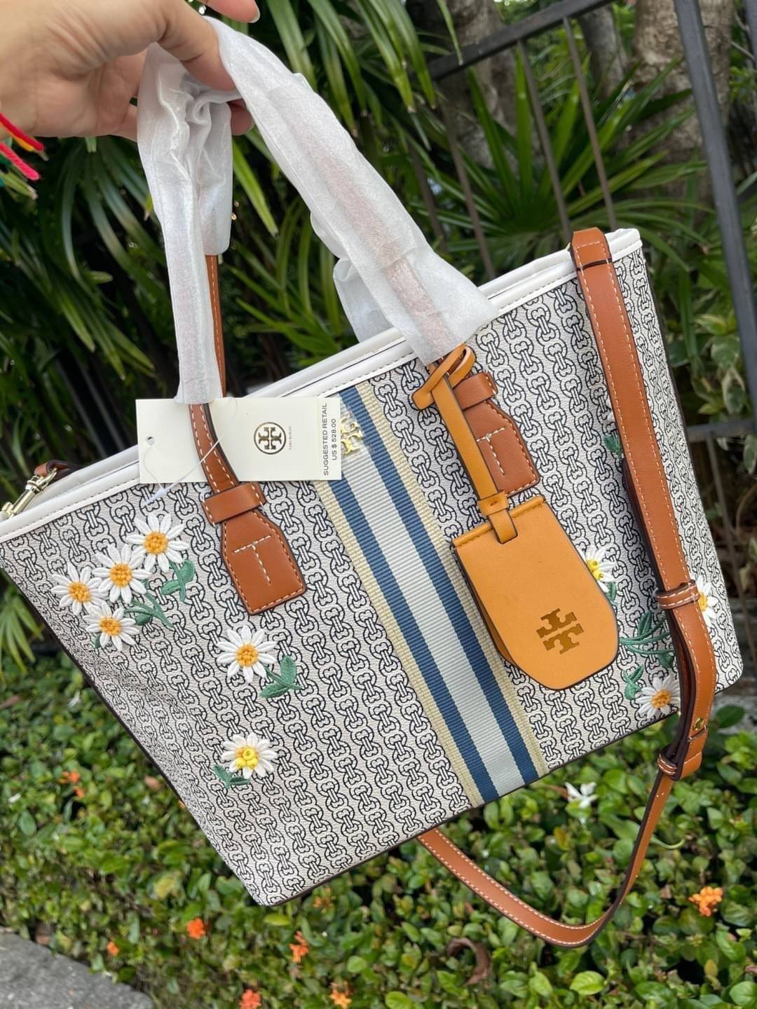 Tory burch Gemini Canvas Applique Small Tote Bag กระเป๋าสุดปังจากทอรี่ เบริช์(Tory Burch) อย่างเจมิไนลิงค์ ในทรง tote bag มีเอกลักษณ์โดดเด่นที่ลายทางตรงกลาง มีการพิมพ์แพทเทิรน์โซ่แบบเรียบหรู เพิ่มความน่ารักจากดอกเดรซี่ที่ถูกจัดวางให้ดูมีสีสัน มีสายสะพายให