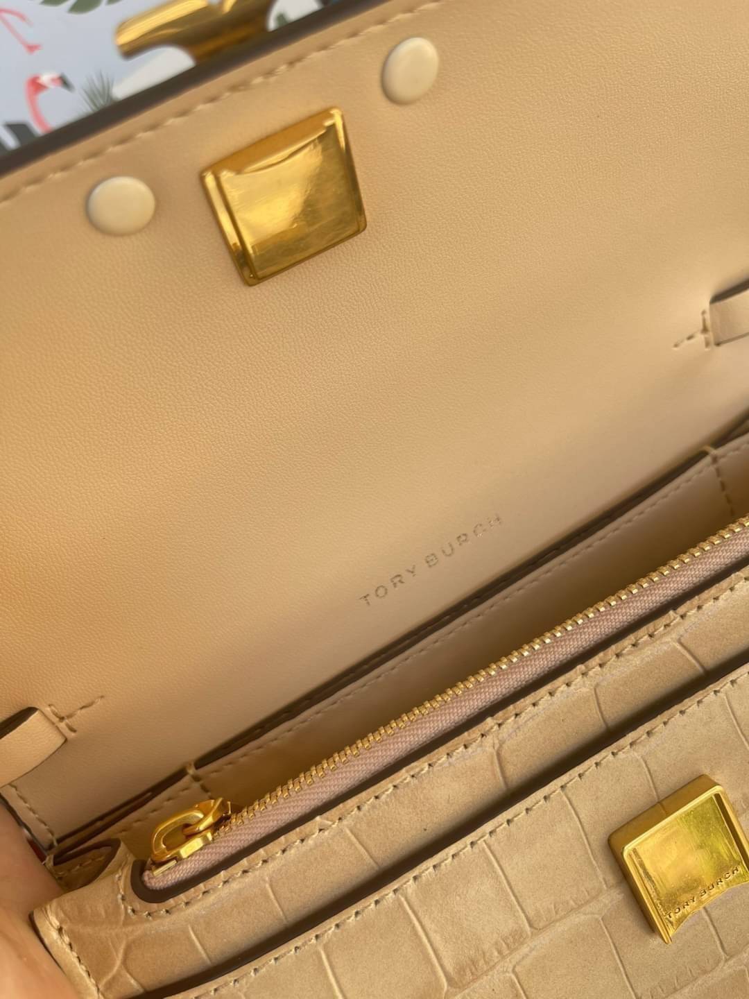 Tory Burch Eleanor Crocodile-Embossed Phone Crossbody Bag จุดเด่นของรุ่นนี้คือดีไซน์ออกมาในสไตล์คลาสสิกที่มาพร้อมกับฮาร์ดแวร์ที่ทำจากวัสดุทองเหลืองและสายสะพายโซ่เกลียวสีทอง ซึ่งการออกแบบได้รับแรงบันดาลใจมาจากเครื่องประดับ รูปทรงกะทัดรัดจึงสามารถสะพายใช้งา